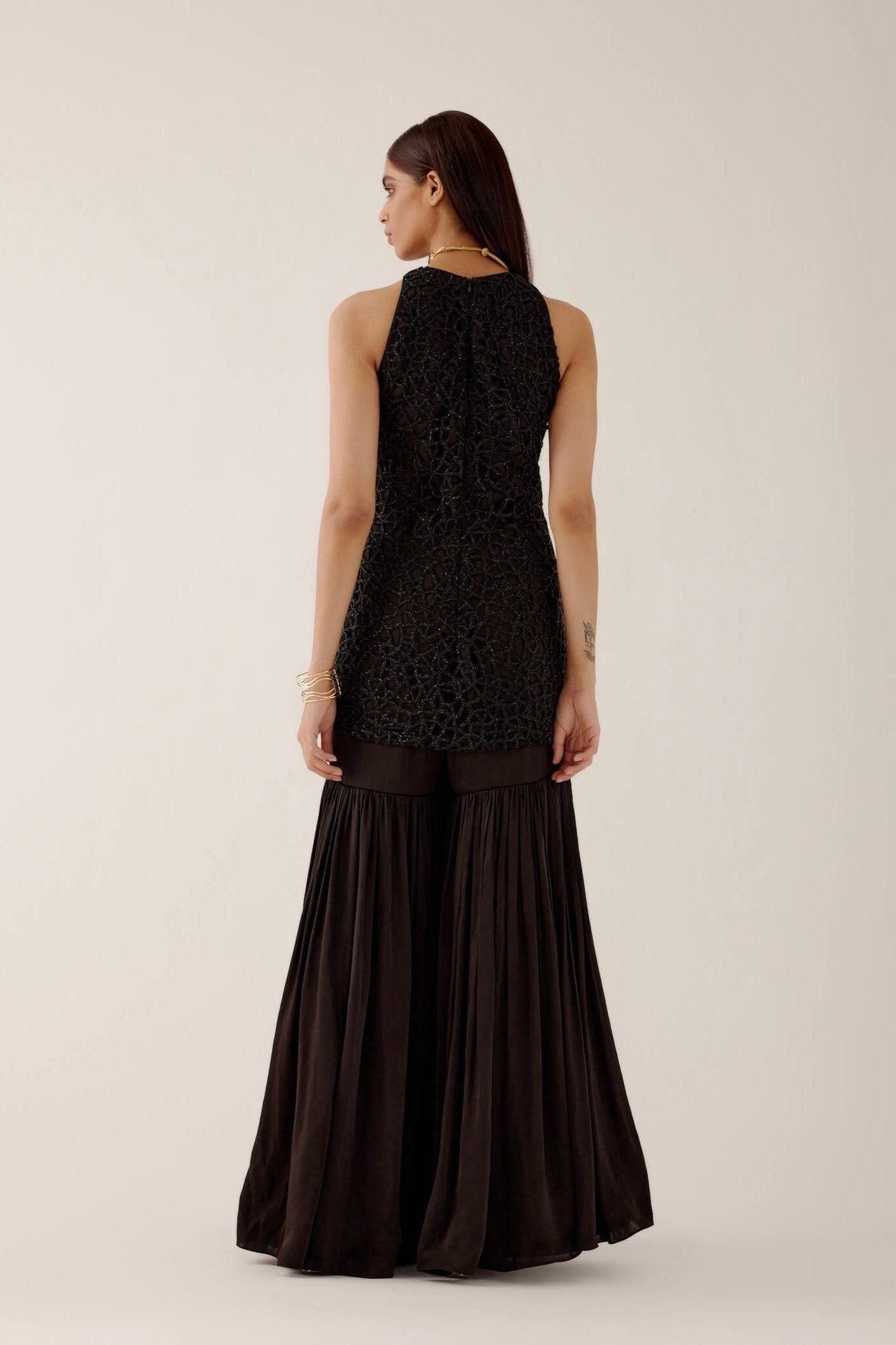 The Anika Gharara is a halter neck, cutwork, hand-embroidered dress paired with bamber satin gharara pants.