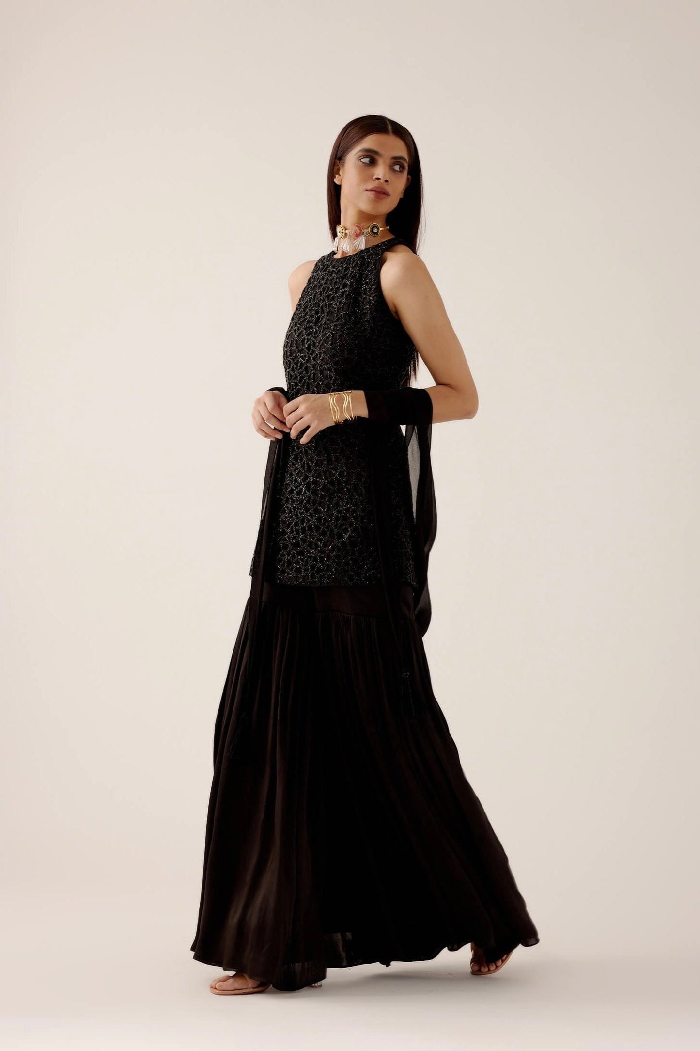 The Anika Gharara is a halter neck, cutwork, hand-embroidered dress paired with bamber satin gharara pants.