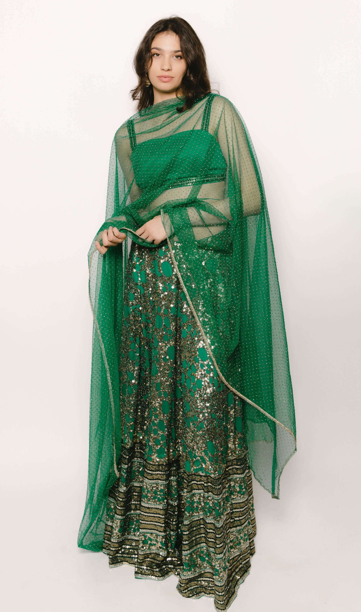 The Detachable Lehenga features a sequin-adorned skirt, criss-cross back blouse, a and delicate net dupatta. With a removable portion, it effortlessly transforms into a shorter skirt for a night of dancing.