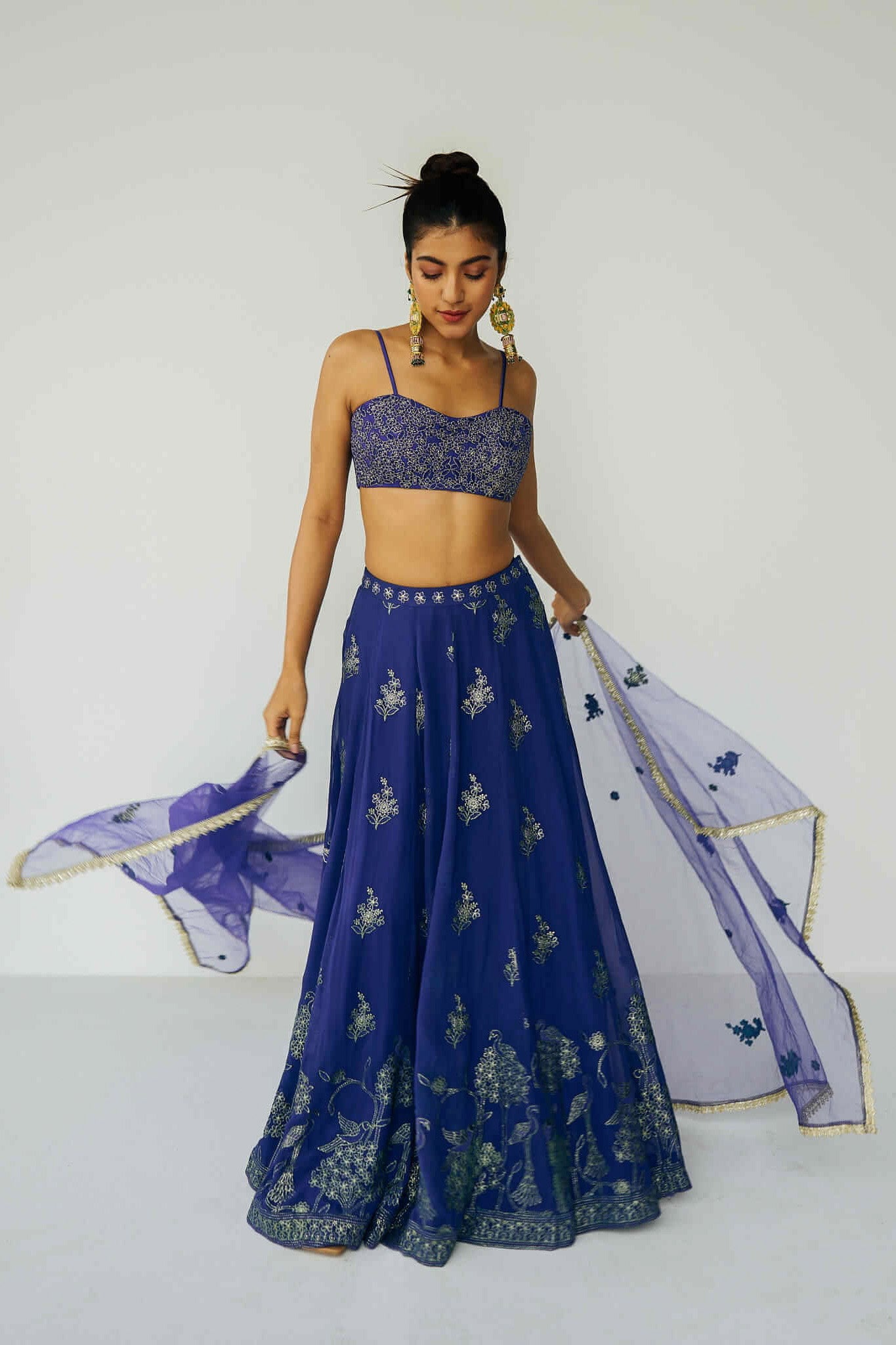 A woman wearing a bright blue embroidered top and skirt with an embroidered dupatta.