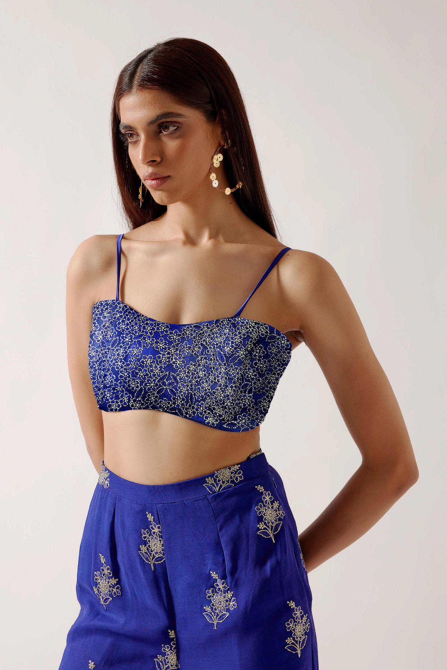 The embroidered Manali Set consists of a blue vest, bra top, and flared pants.
