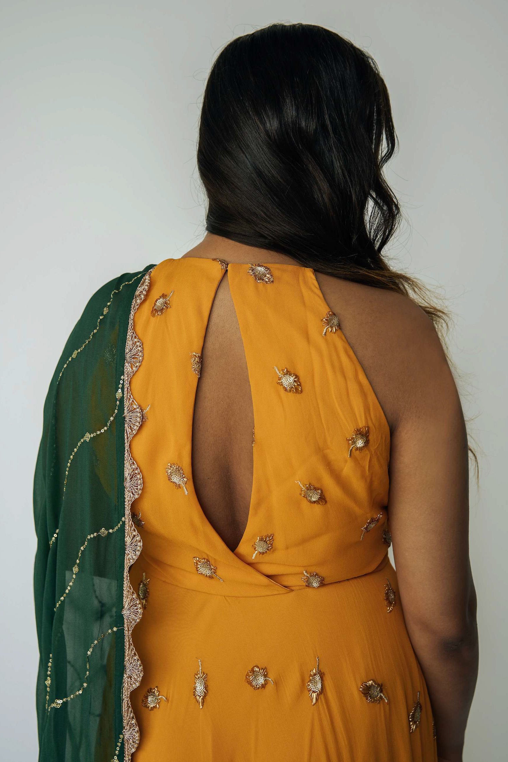 The Nila Anarkali has a halter neck-cut bodice, flowing waistline, and is paired with a contrasting silk crepe dupatta.