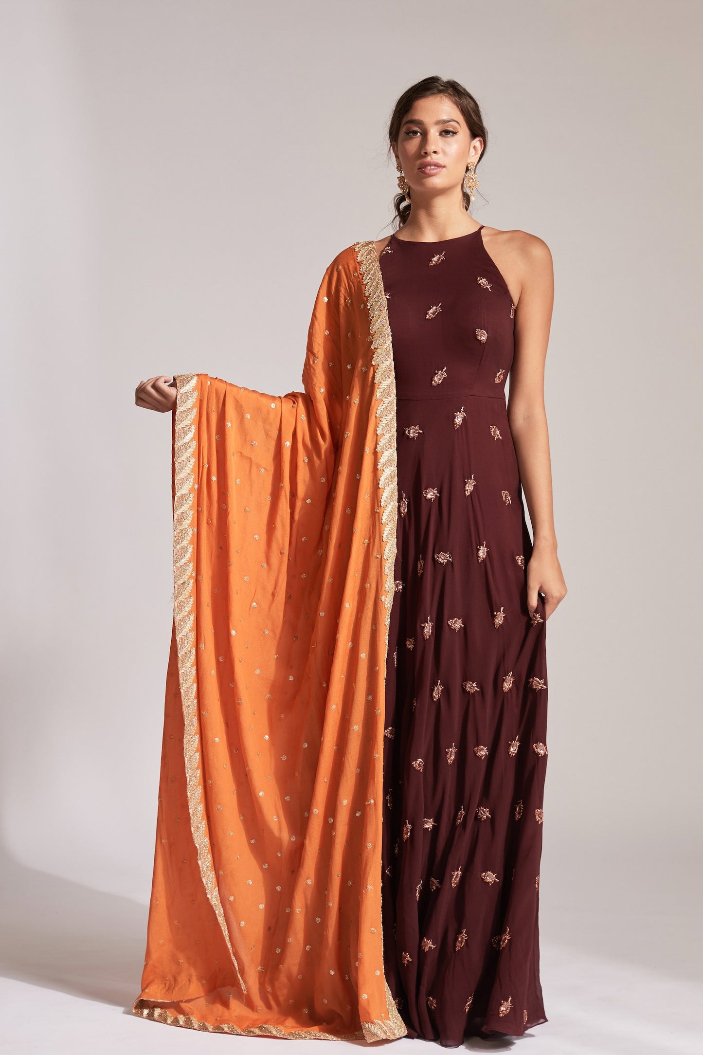 The Nila Anarkali has a halter neck-cut bodice, flowing waistline, and is paired with a contrasting silk crepe dupatta.