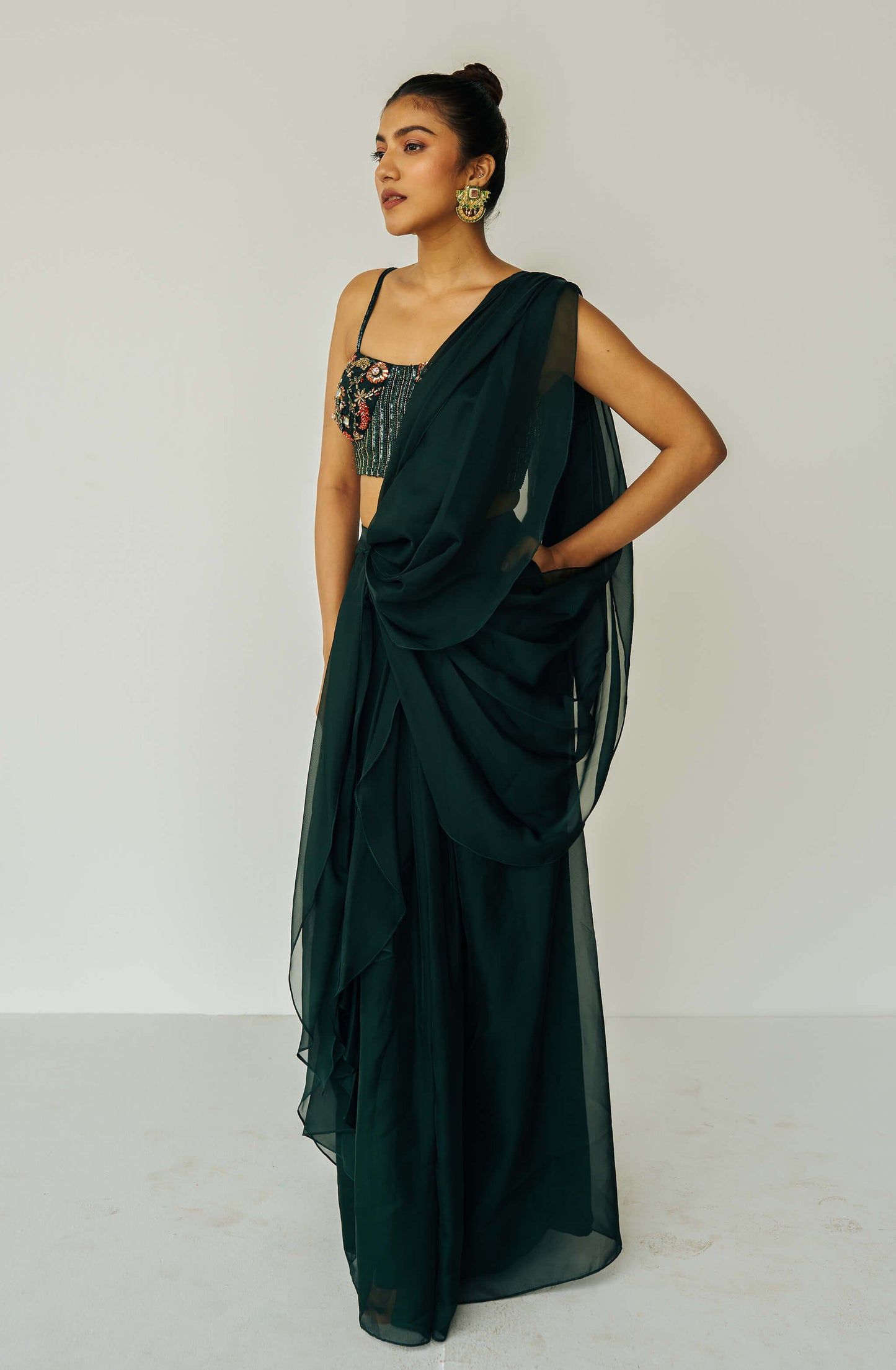 The Adya Drape Saree makes it easy to get the saree look without any pleating and features a shiny organaza skirt with an attached drape + a hand embroidered, bustier top.