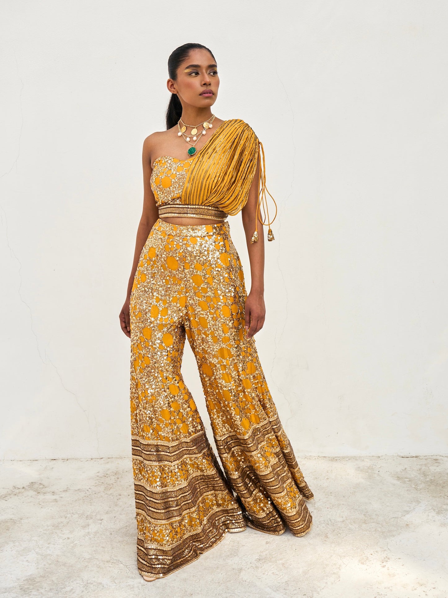 The sequined Tanvi Palazzo Set consists of a one-shoulder adjustable top and flared palazzo pants.