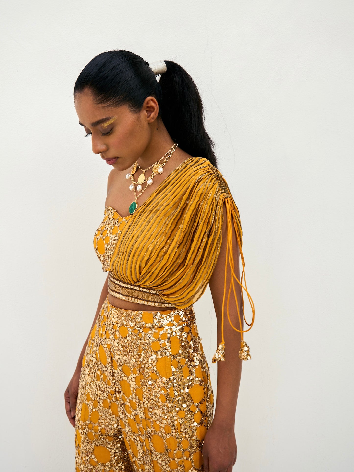 The sequined Tanvi Palazzo Set consists of a one-shoulder adjustable top and flared palazzo pants.