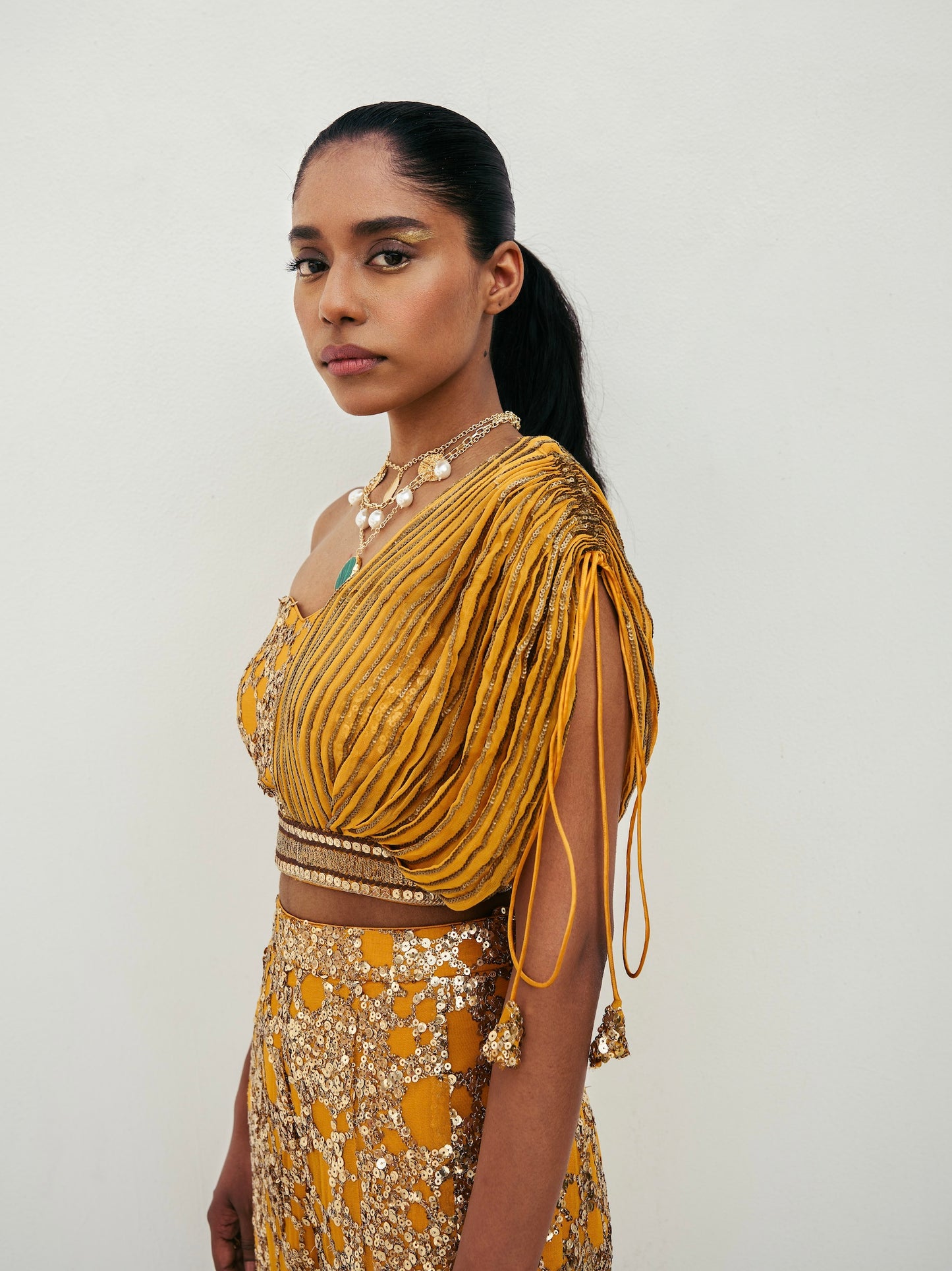 The sequined Tanvi Palazzo Set consists of a one-shoulder adjustable top and flared palazzo pants.