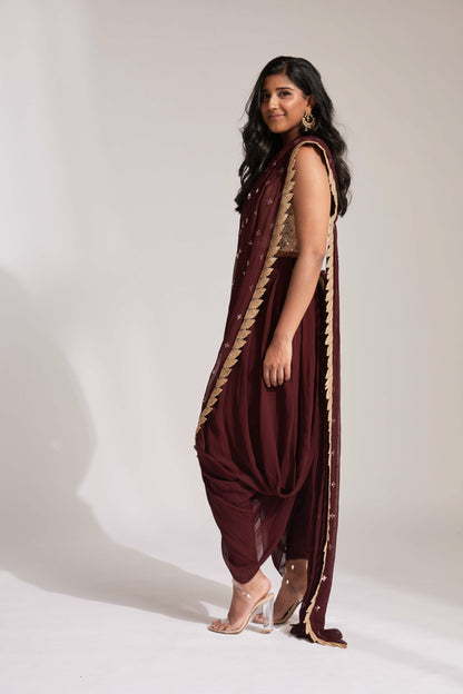 The Tara Dhoti takes the elegance of a saree's drape and combines it with the comfort of a dhoti pant. The booti-work drape is attached to the outfit and is paired with a mirror work blouse.