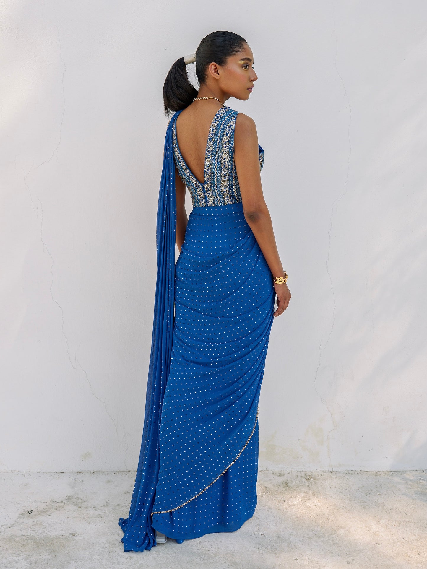 This outfit features a skirt with attached wrap-around draping - all pre-stitched so you can put the outfit together in 30 seconds or less. The drape has small gold embellishments throughout and the piece is paired with a gold hand-embroidered v-neck blouse.