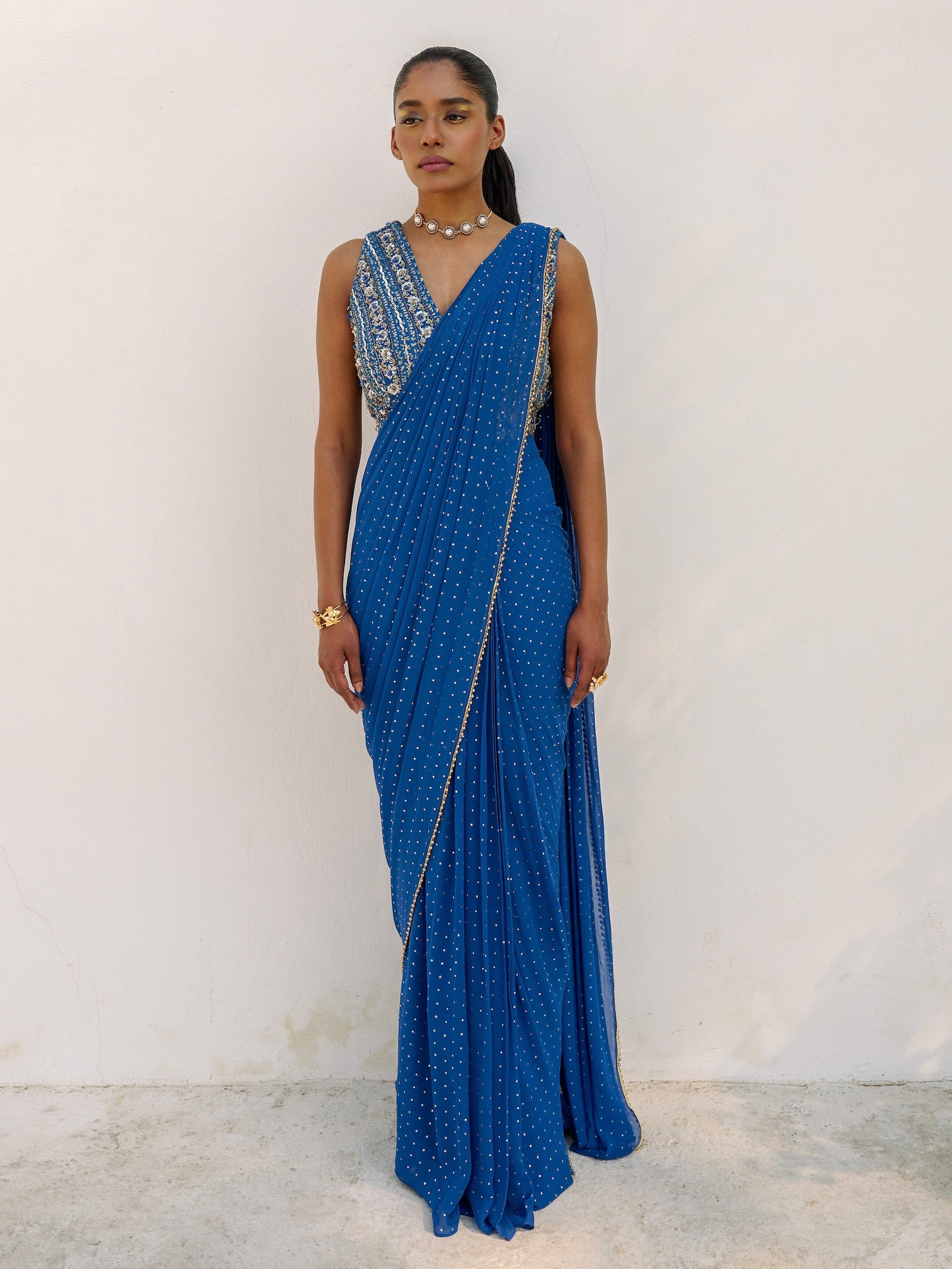 This outfit features a skirt with attached wrap-around draping - all pre-stitched so you can put the outfit together in 30 seconds or less. The drape has small gold embellishments throughout and the piece is paired with a gold hand-embroidered v-neck blouse.