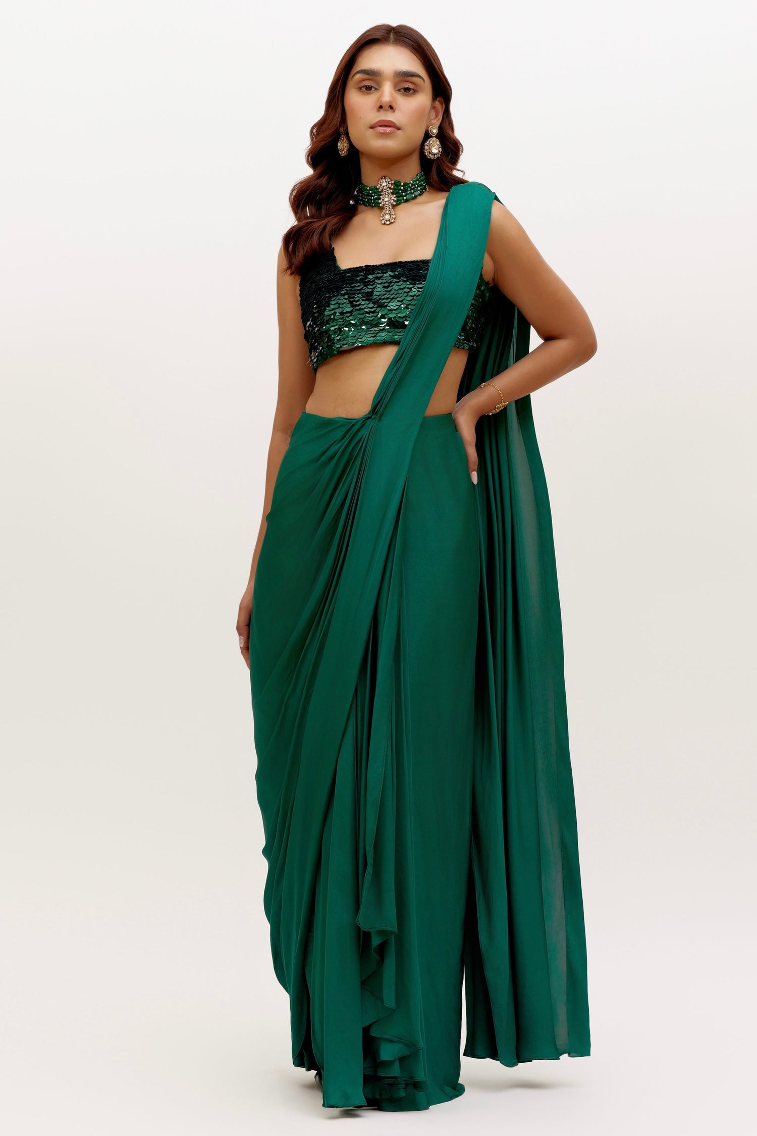 The Raya Drape Saree includes a sequin square-neck blouse and a silky, figure-flattering skirt with an attached drape in a deep, rich emerald color. The attached drape just has to be wrapped around you to complete the look in less than 5 seconds.
