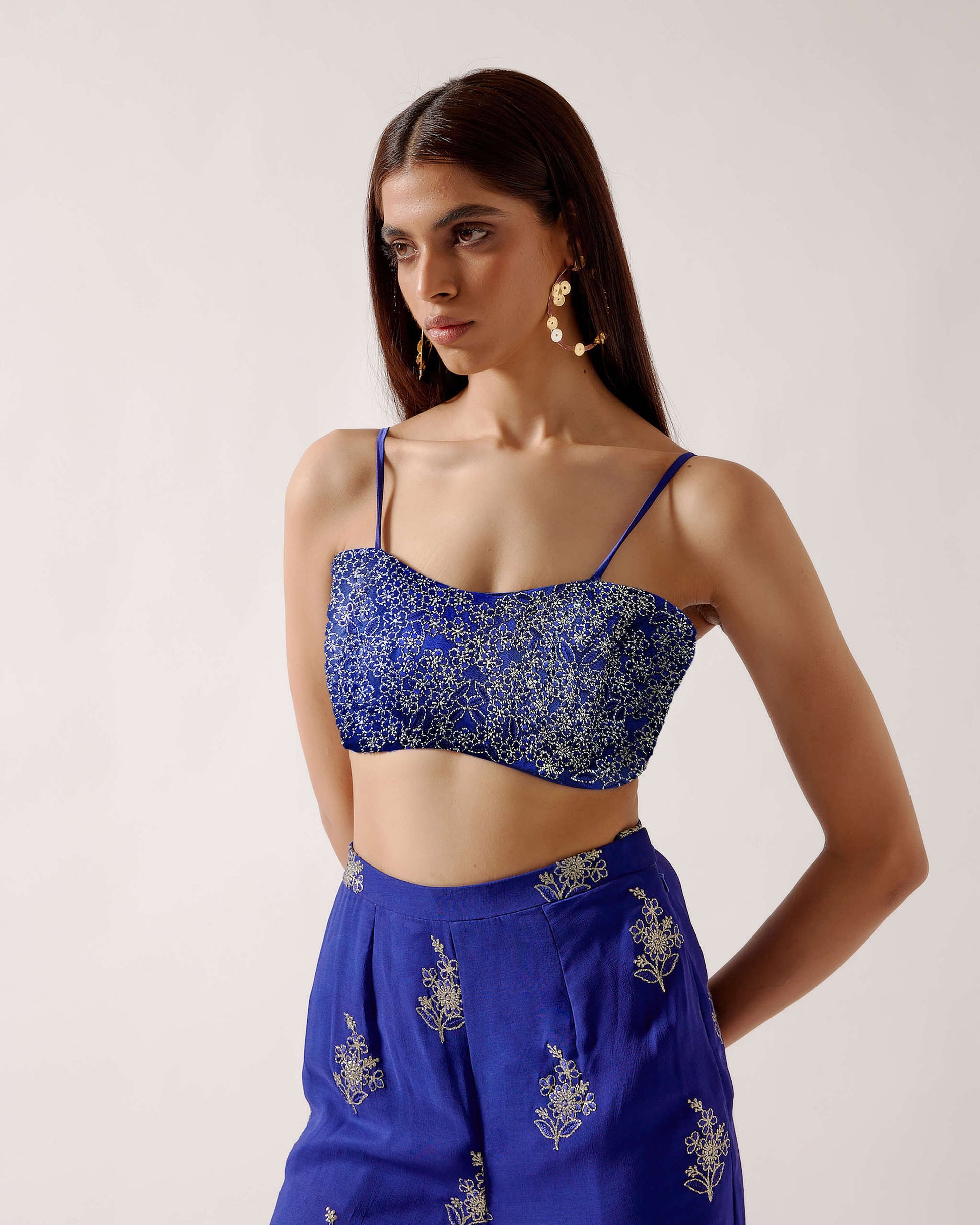 The embroidered Manali Set consists of a blue vest, bra top, and flared pants. 