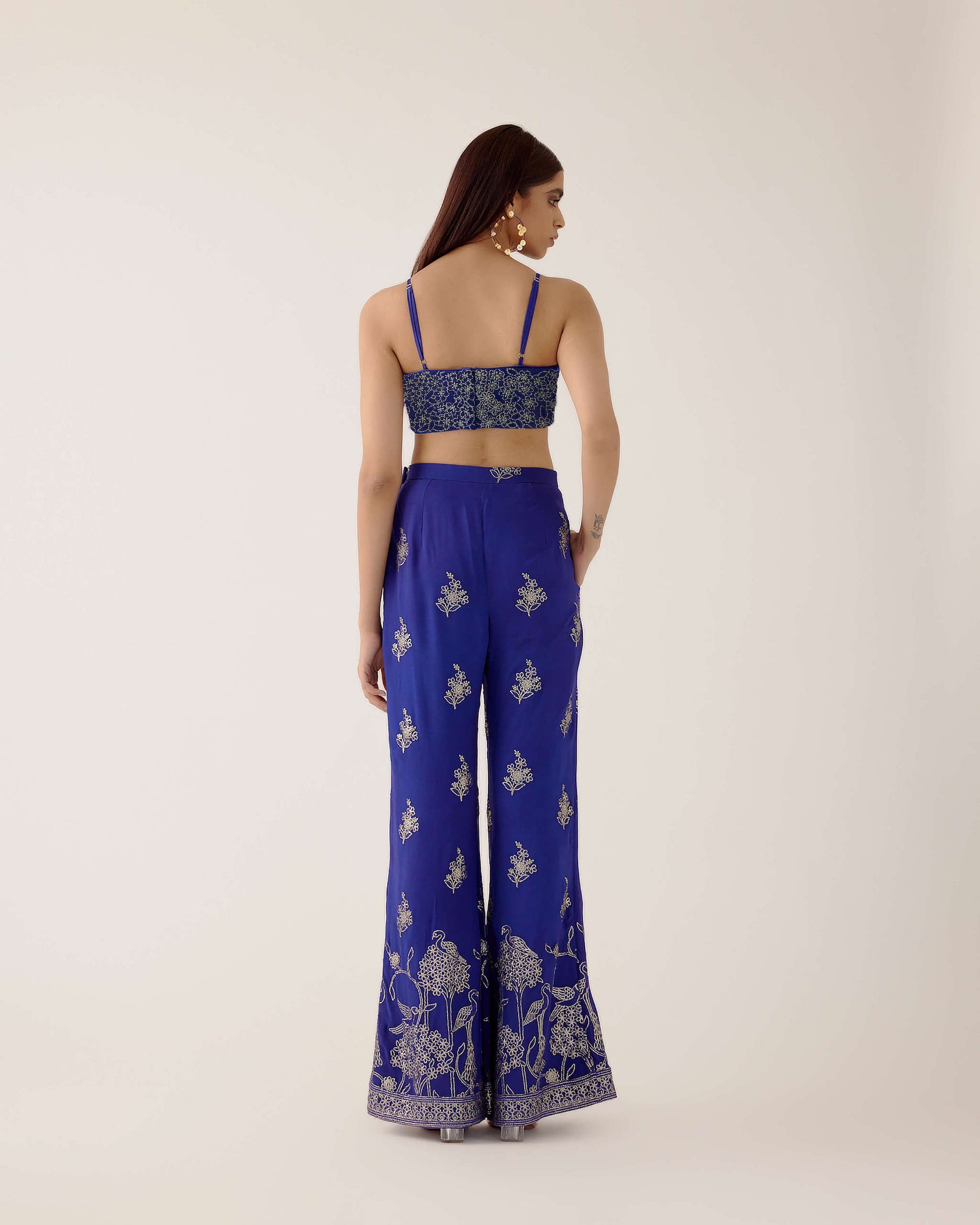 The embroidered Manali Set consists of a blue vest, bra top, and flared pants. 