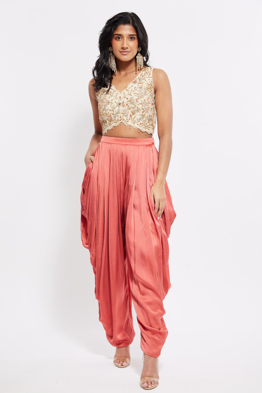 The Sneh Dhoti takes the elegance of a saree's drape and combines it with the comfort of a dhoti pant. Made from bamboo satin, the dhoti pant is paired with a hand-embroidered blouse featuring scalloped edges, floral motifs, and crystal beadwork. This outfit includes an organza dupatta adorned with scattered floral motifs and delicate beadwork. Its ruffle trim offers versatility, allowing it to be styled as a shawl.
