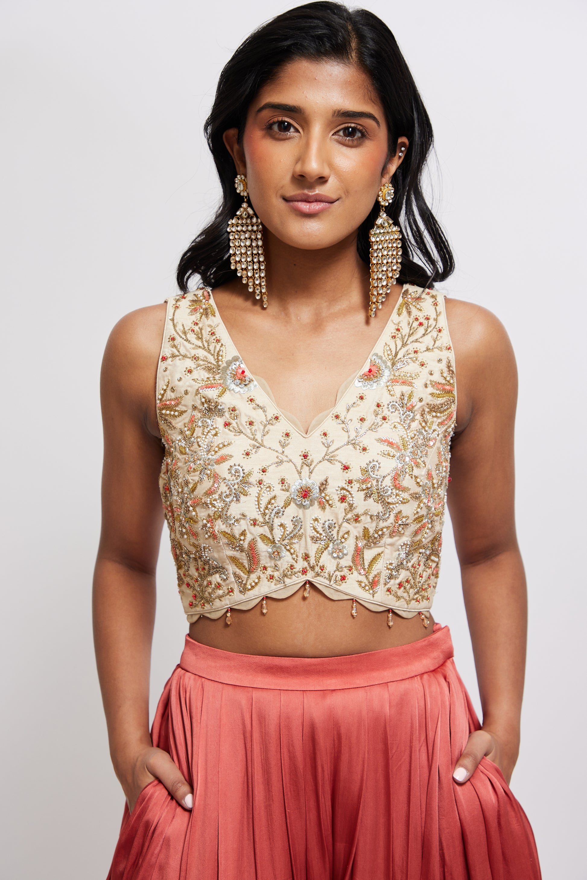 The Sneh Dhoti takes the elegance of a saree's drape and combines it with the comfort of a dhoti pant. Made from bamboo satin, the dhoti pant is paired with a hand-embroidered blouse featuring scalloped edges, floral motifs, and crystal beadwork. This outfit includes an organza dupatta adorned with scattered floral motifs and delicate beadwork. Its ruffle trim offers versatility, allowing it to be styled as a shawl.