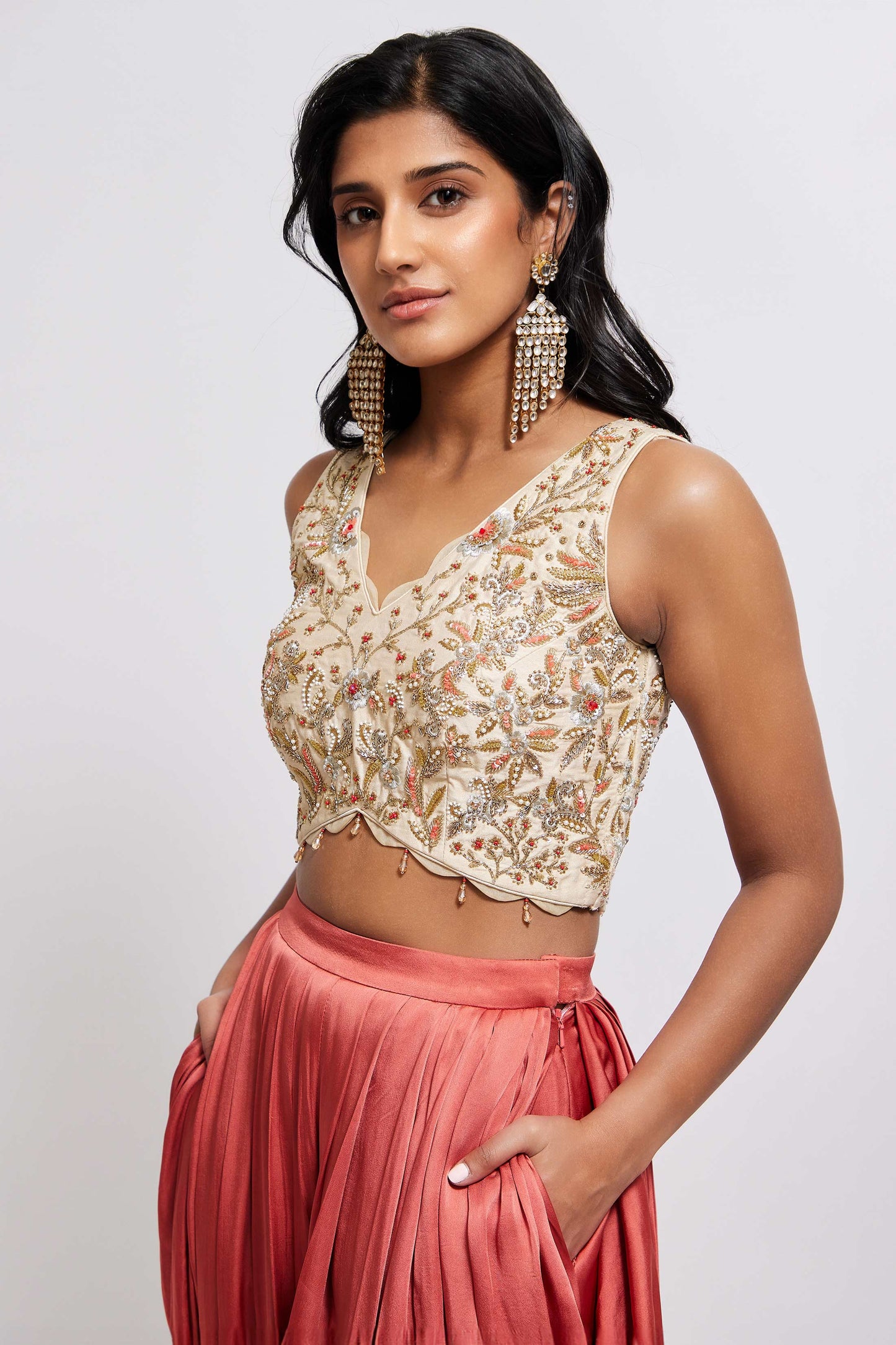 The Sneh Dhoti takes the elegance of a saree's drape and combines it with the comfort of a dhoti pant. Made from bamboo satin, the dhoti pant is paired with a hand-embroidered blouse featuring scalloped edges, floral motifs, and crystal beadwork. This outfit includes an organza dupatta adorned with scattered floral motifs and delicate beadwork. Its ruffle trim offers versatility, allowing it to be styled as a shawl.
