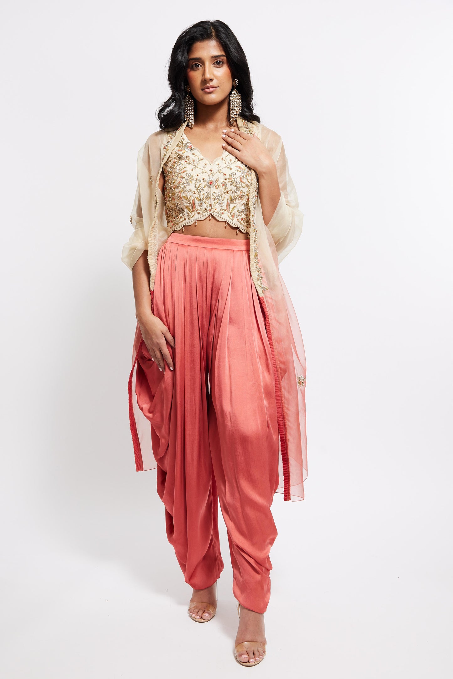 The Sneh Dhoti takes the elegance of a saree's drape and combines it with the comfort of a dhoti pant. Made from bamboo satin, the dhoti pant is paired with a hand-embroidered blouse featuring scalloped edges, floral motifs, and crystal beadwork. This outfit includes an organza dupatta adorned with scattered floral motifs and delicate beadwork. Its ruffle trim offers versatility, allowing it to be styled as a shawl.