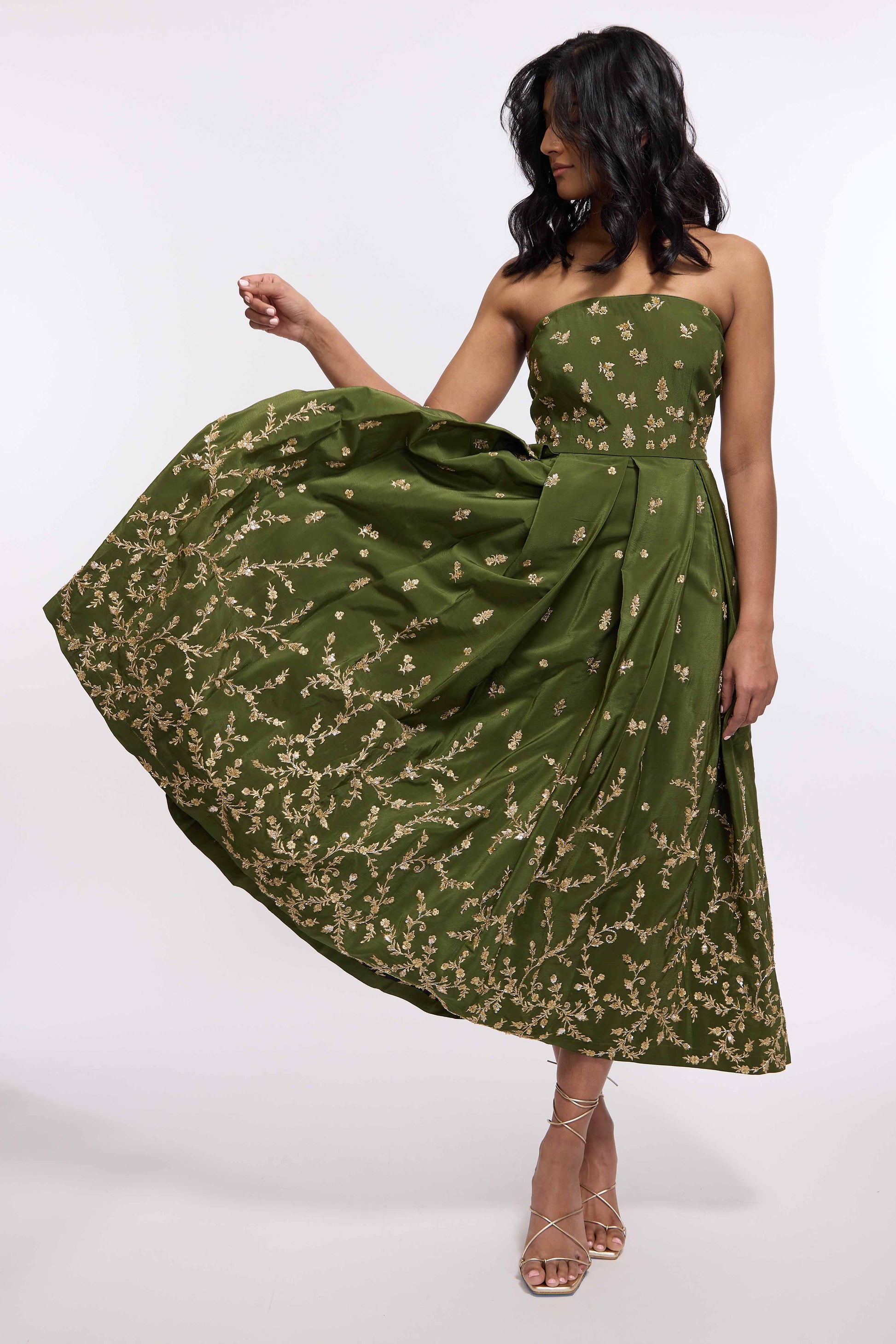 Woman wearing green midi length dress with Indian inspired embroidery