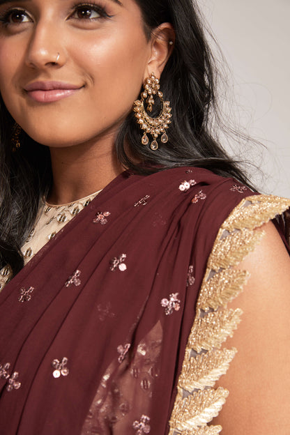 The Tara Dhoti takes the elegance of a saree's drape and combines it with the comfort of a dhoti pant. The booti-work drape is attached to the outfit and is paired with a mirror work blouse.