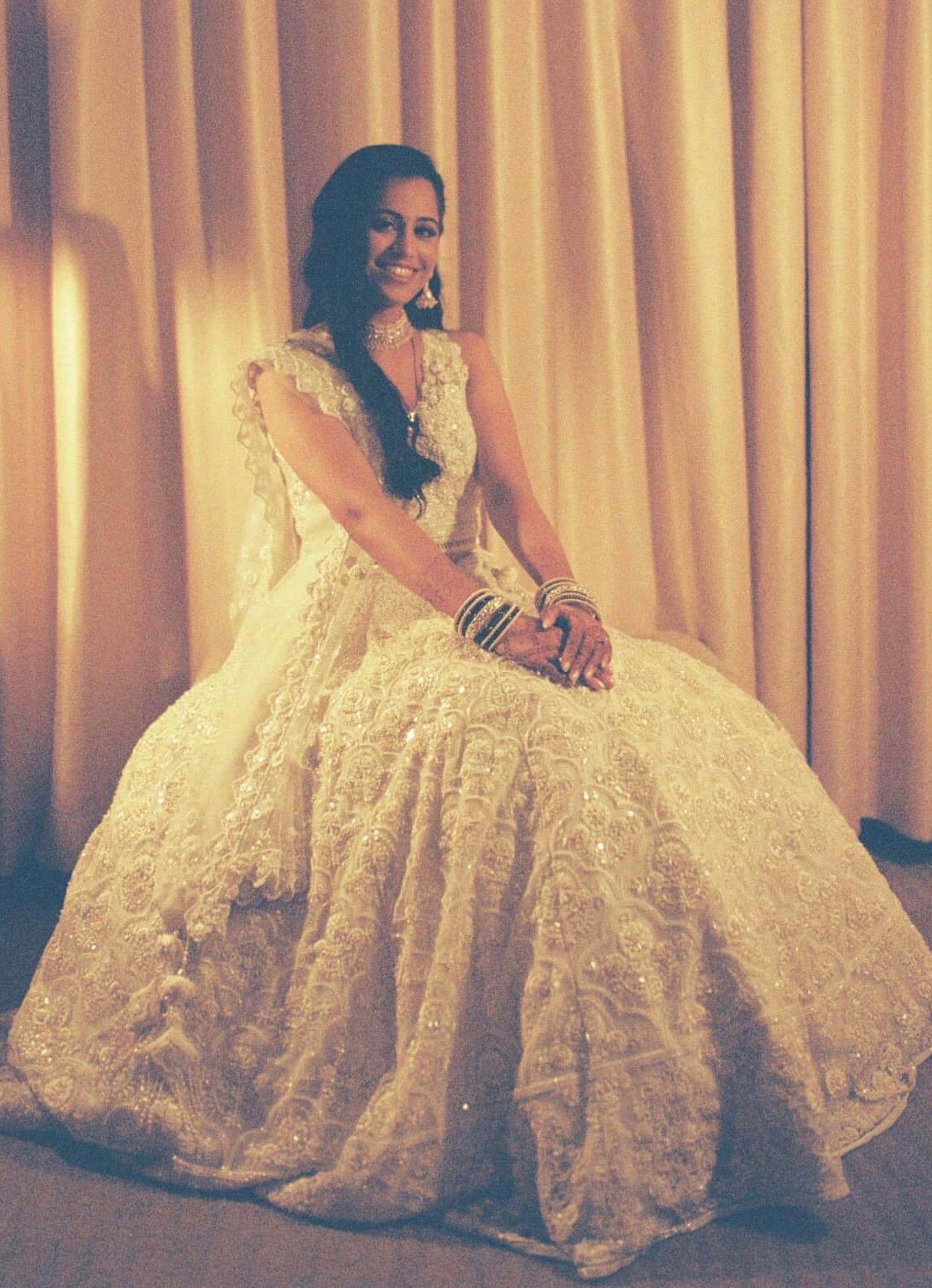 The Rucha Lehenga is a white hand-embroidered lehenga adorned with Swarovski crystals. It features a v-neck blouse with two tie details in the back. It comes with a completely detachable can-can. 