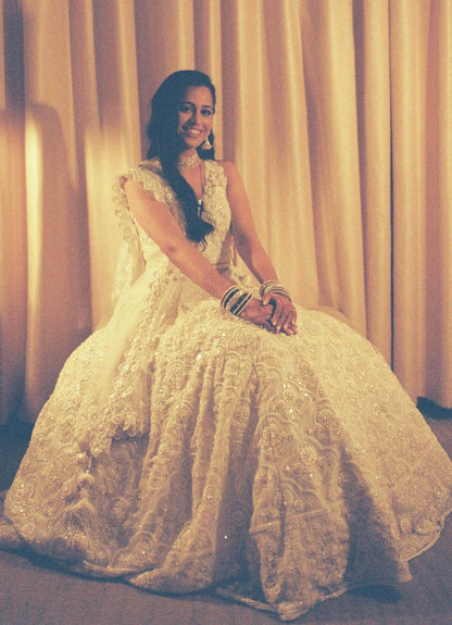 The Rucha Lehenga is a white hand-embroidered lehenga adorned with Swarovski crystals. It features a v-neck blouse with two tie details in the back. It comes with a completely detachable can-can. 