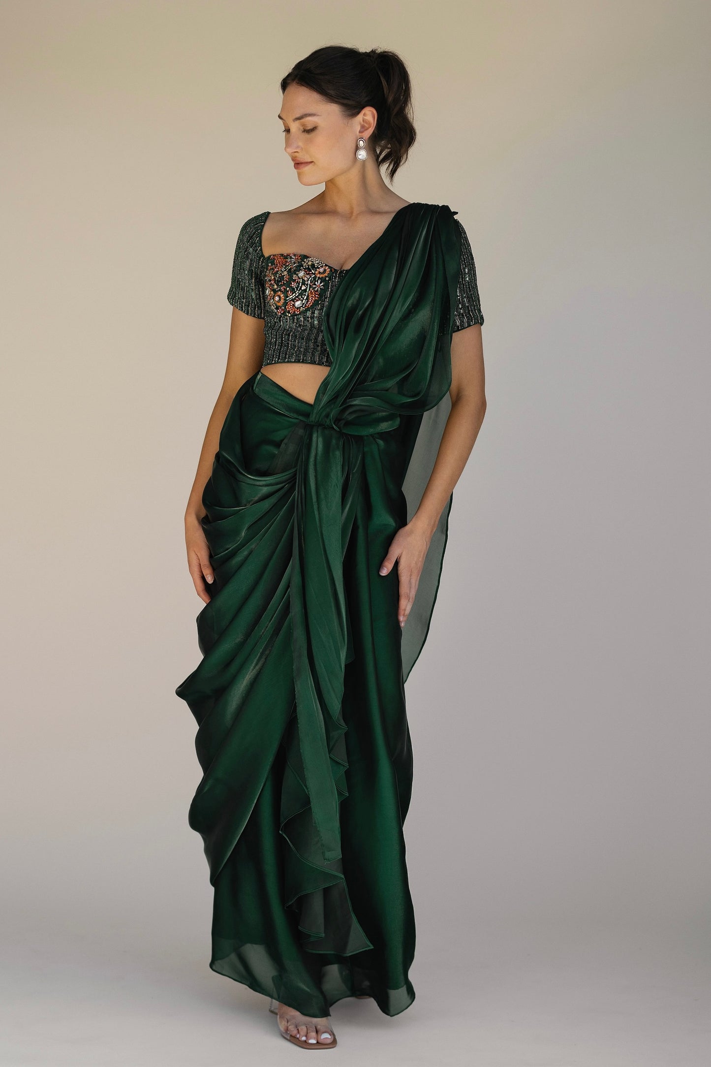 The Adya Drape Saree makes it easy to get the saree look without any pleating and features a shiny organaza skirt with an attached drape + a hand embroidered, bustier top.&nbsp;