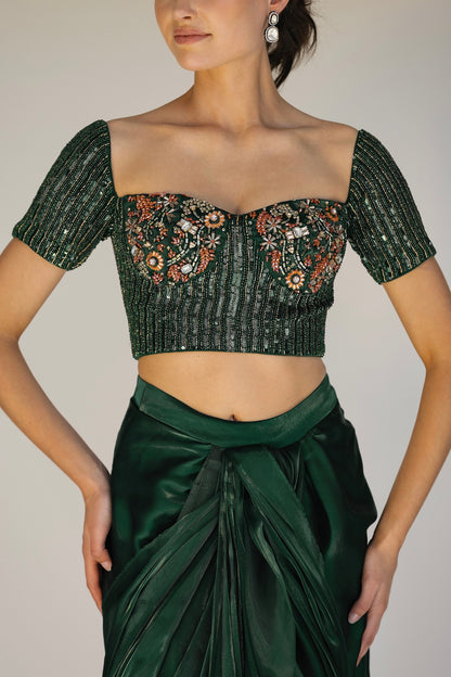 The Adya Drape Saree makes it easy to get the saree look without any pleating and features a shiny organaza skirt with an attached drape + a hand embroidered, bustier top.&nbsp;