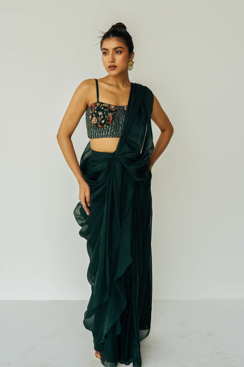 The Adya Drape Saree makes it easy to get the saree look without any pleating and features a shiny organaza skirt with an attached drape + a hand embroidered, bustier top.