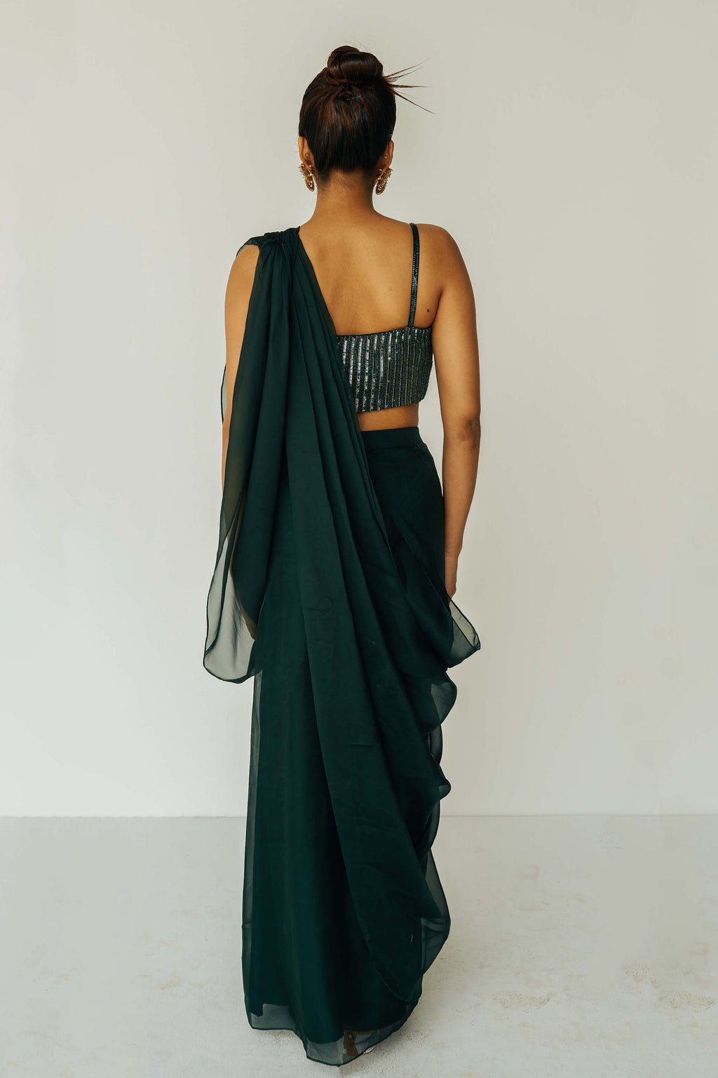 The Adya Drape Saree makes it easy to get the saree look without any pleating and features a shiny organaza skirt with an attached drape + a hand embroidered, bustier top.