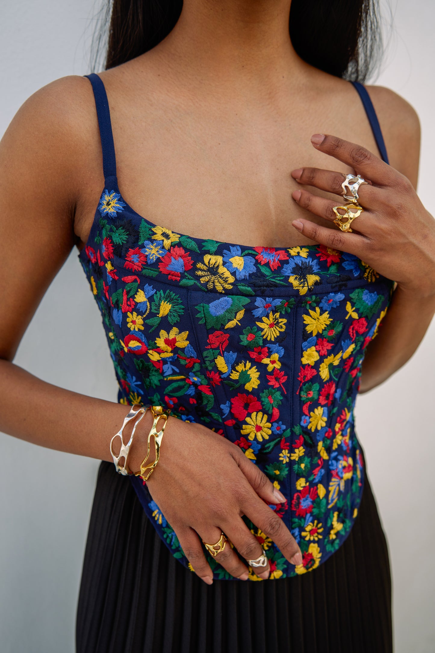The Zinnia Top is a corset style with embroidered, multicolored flowers and adjustable straps. 