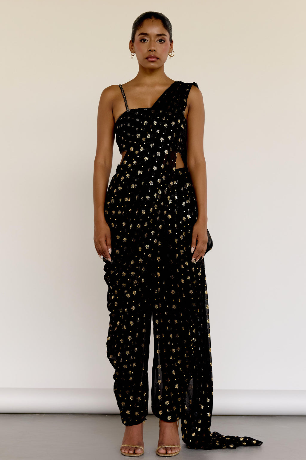 The Farah Dhoti set features a flattering midriff-baring top, flowy dhoti pants made for dancing, and an attached dupatta that drapes perfectly every time—no pleating, no fuss. The gold foil print adds just the right amount of texture and attention to detail.