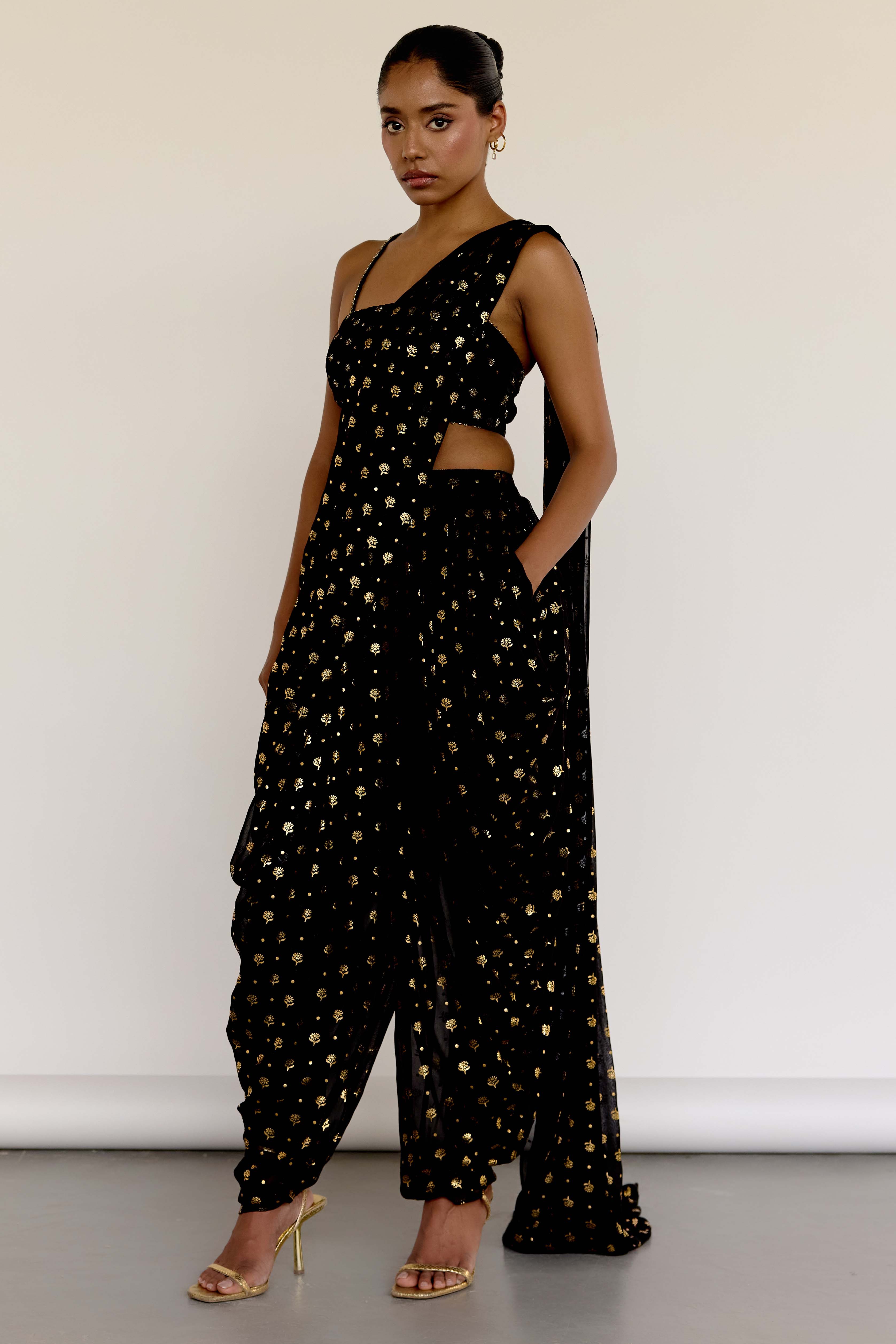 The Farah Dhoti set features a flattering midriff-baring top, flowy dhoti pants made for dancing, and an attached dupatta that drapes perfectly every time—no pleating, no fuss. The gold foil print adds just the right amount of texture and attention to detail.