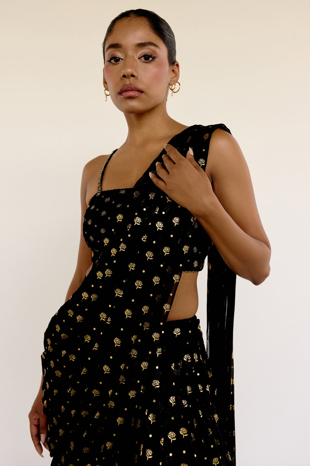 The Farah Dhoti set features a flattering midriff-baring top, flowy dhoti pants made for dancing, and an attached dupatta that drapes perfectly every time—no pleating, no fuss. The gold foil print adds just the right amount of texture and attention to detail.