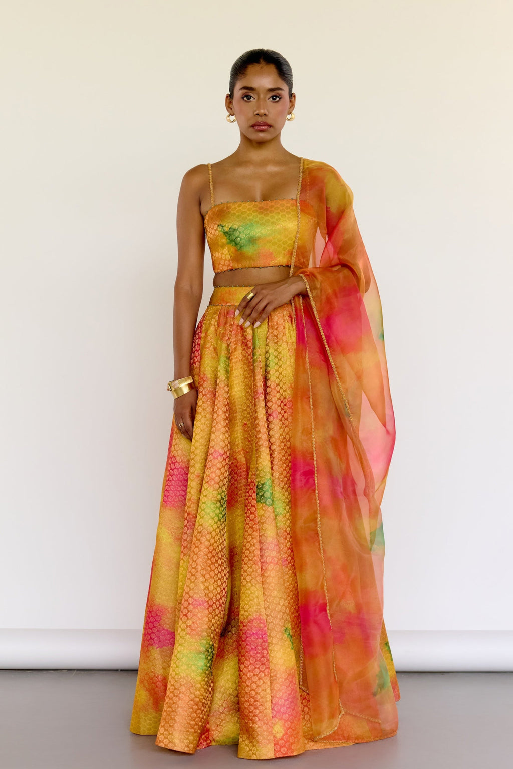 The Holi Lehenga features a printed brocade top with embroidered straps, a high-waisted skirt, and a lightweight printed organza dupatta. An easy lehenga for any celebration.