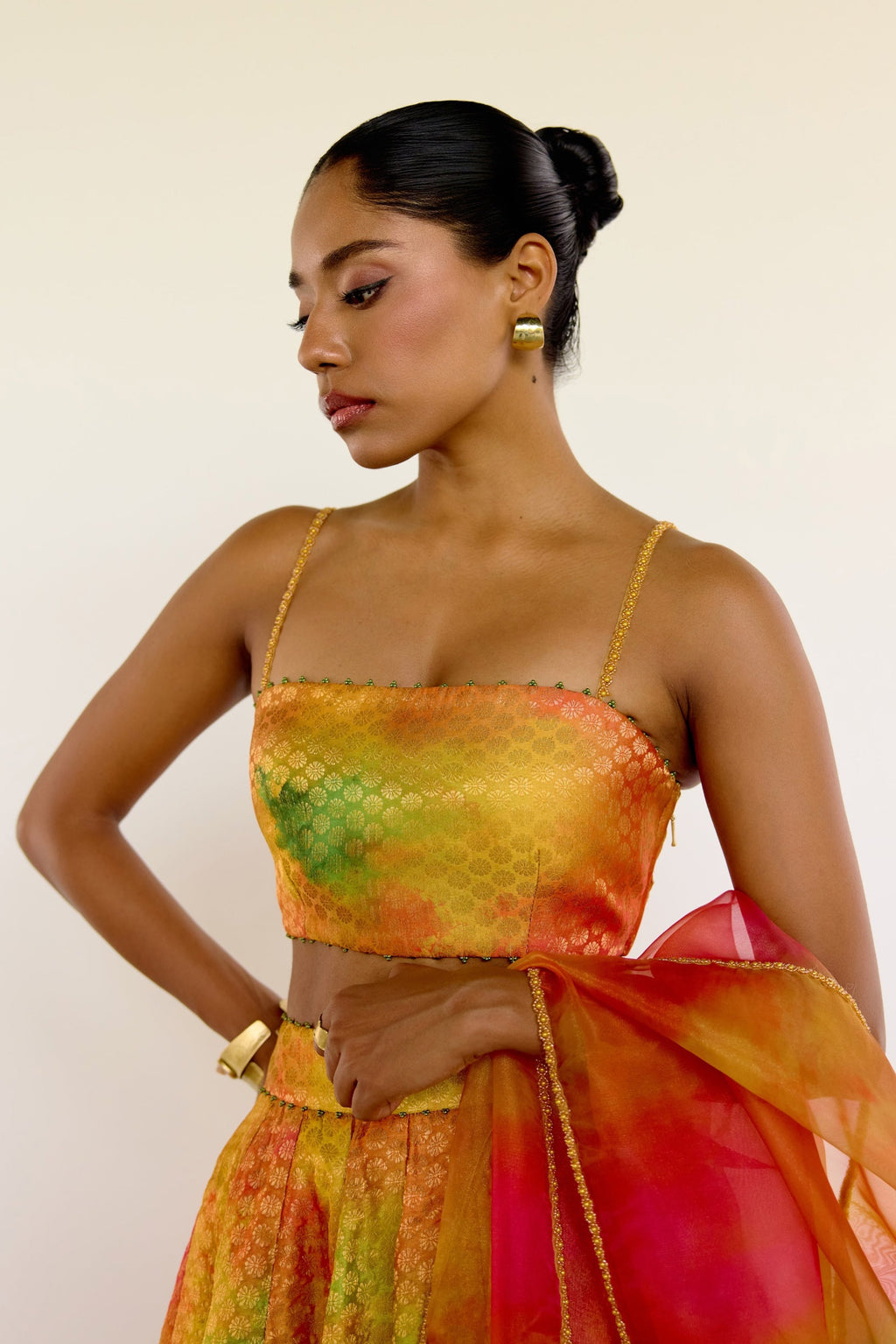 The Holi Lehenga features a printed brocade top with embroidered straps, a high-waisted skirt, and a lightweight printed organza dupatta. An easy lehenga for any celebration.
