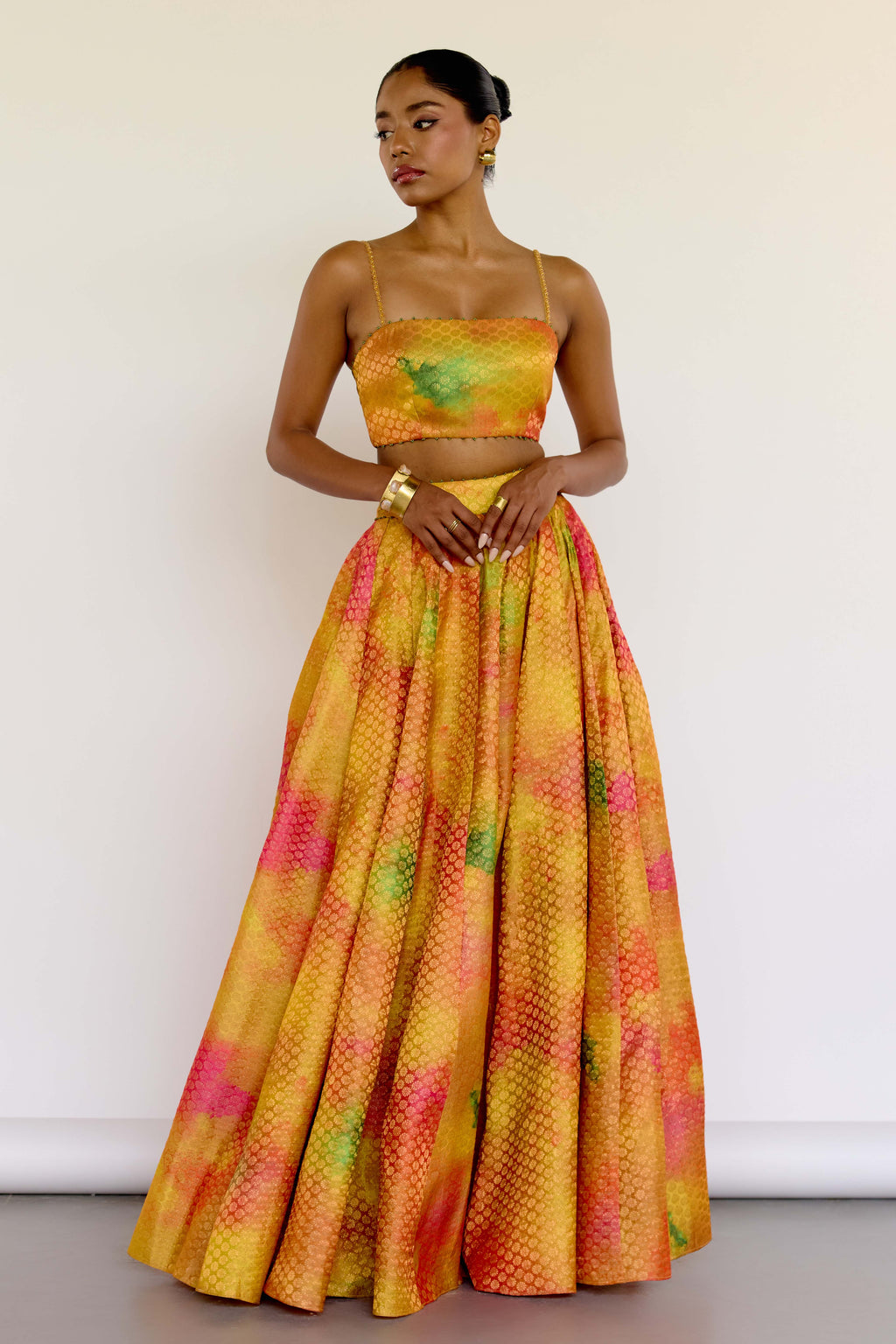 The Holi Lehenga features a printed brocade top with embroidered straps, a high-waisted skirt, and a lightweight printed organza dupatta. An easy lehenga for any celebration.
