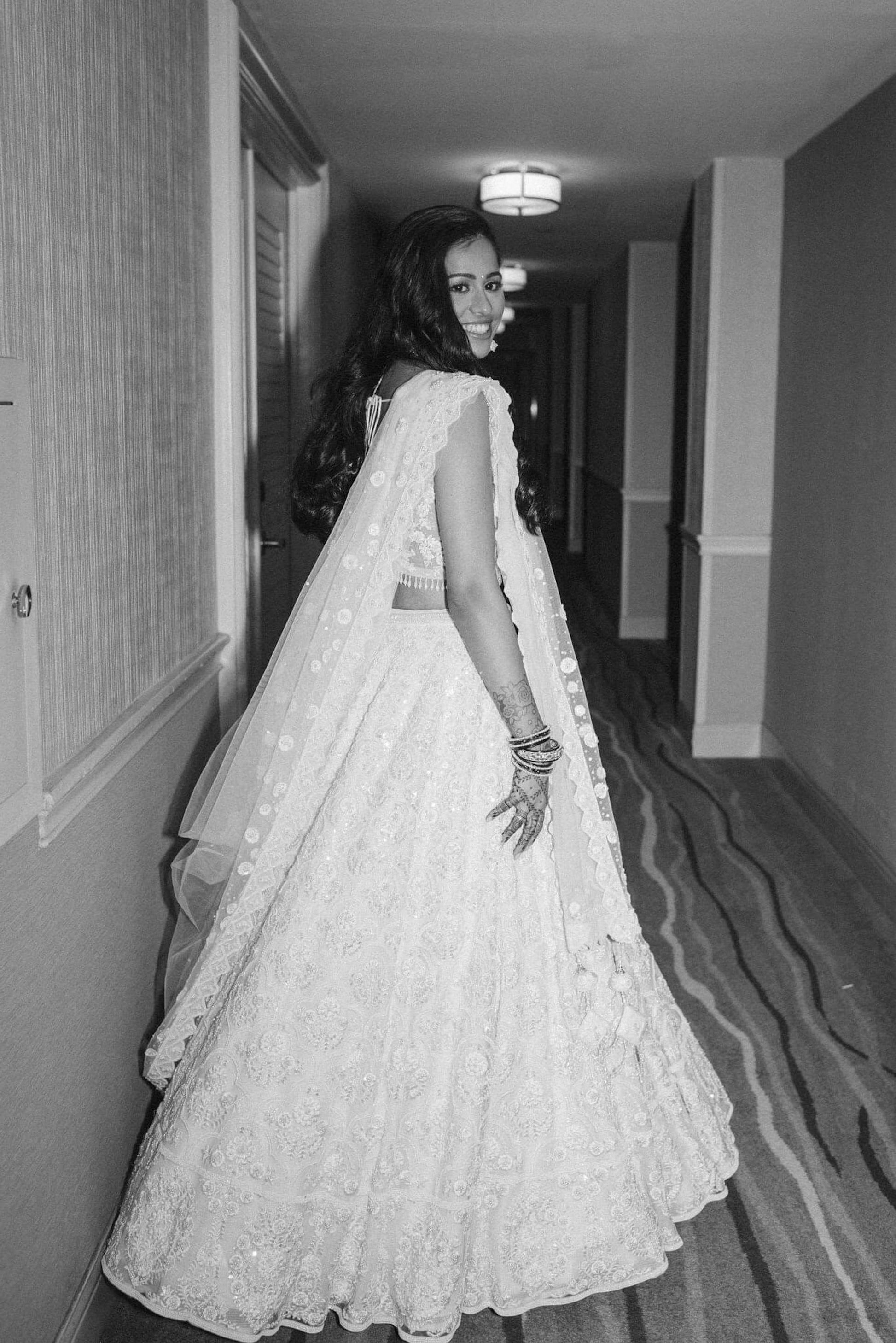 The Rucha Lehenga is a white hand-embroidered lehenga adorned with Swarovski crystals. It features a v-neck blouse with two tie details in the back. It comes with a completely detachable can-can. 