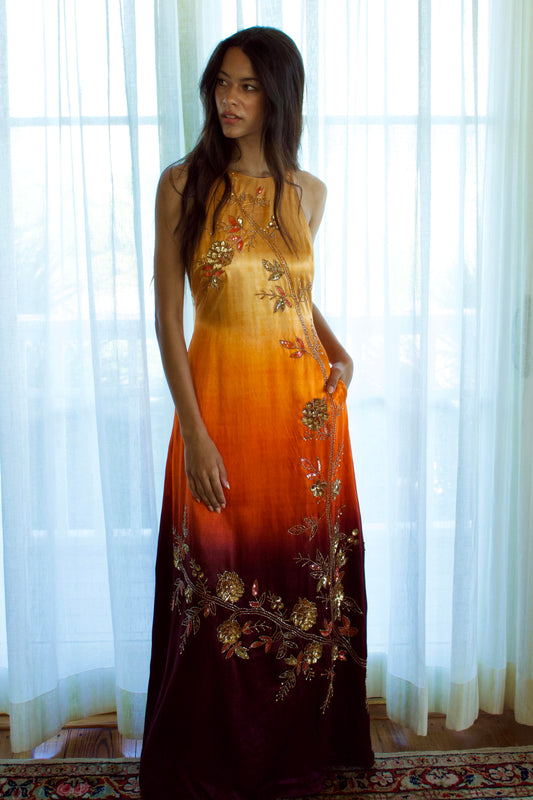 The Mya Anarkali features a high halter neckline and detailed vine and floral embroidery that runs from top to bottom. The ombré color shifts from yellow to orange to brown, and the dress includes pockets for added functionality.