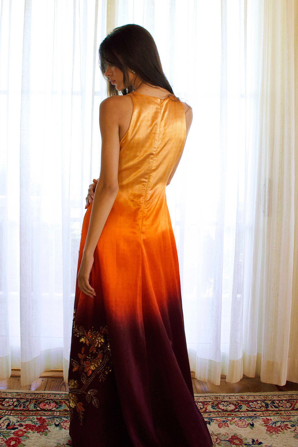 The Mya Anarkali features a high halter neckline and detailed vine and floral embroidery that runs from top to bottom. The ombré color shifts from yellow to orange to brown, and the dress includes pockets for added functionality.