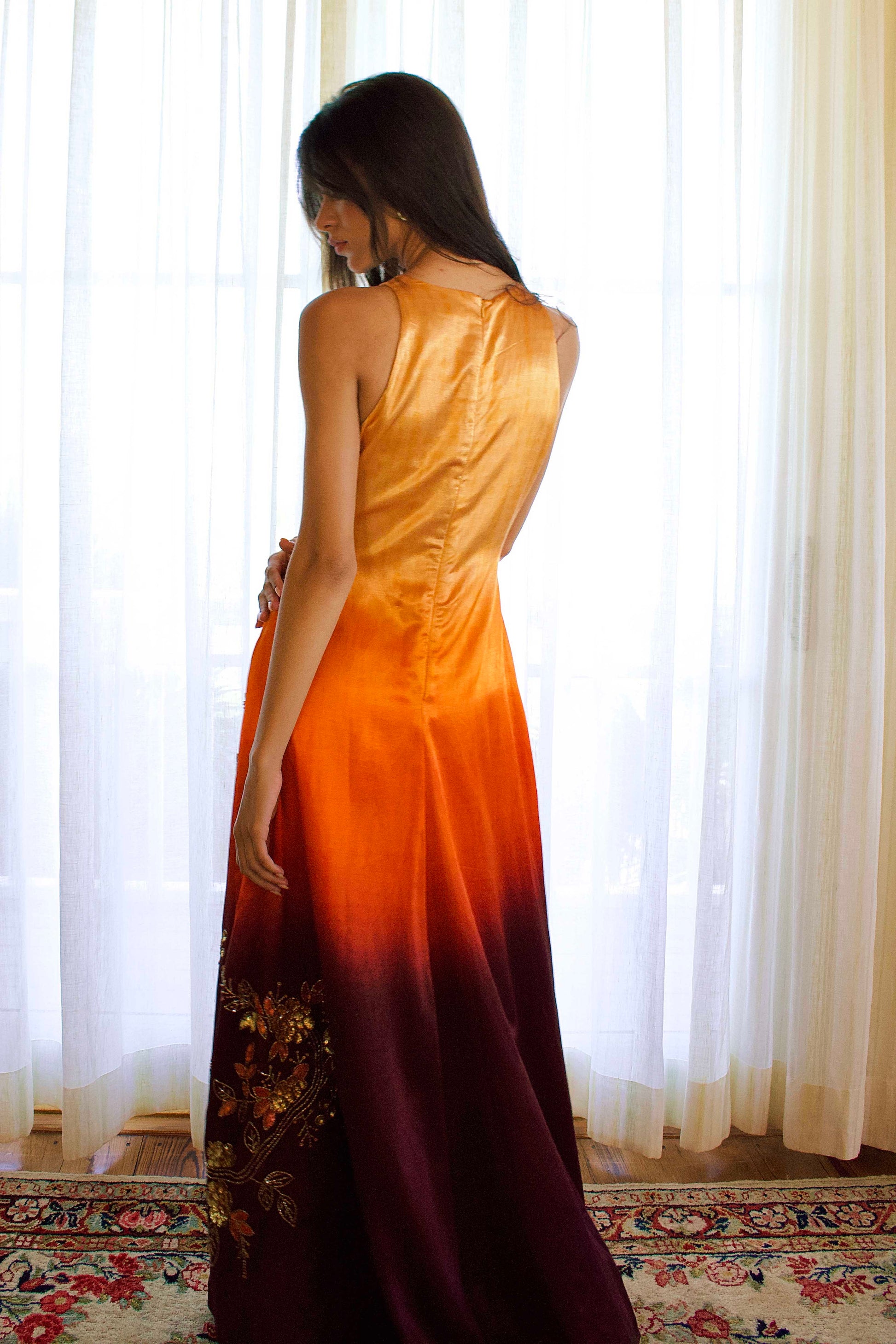 The Mya Anarkali features a high halter neckline and detailed vine and floral embroidery that runs from top to bottom. The ombré color shifts from yellow to orange to brown, and the dress includes pockets for added functionality.