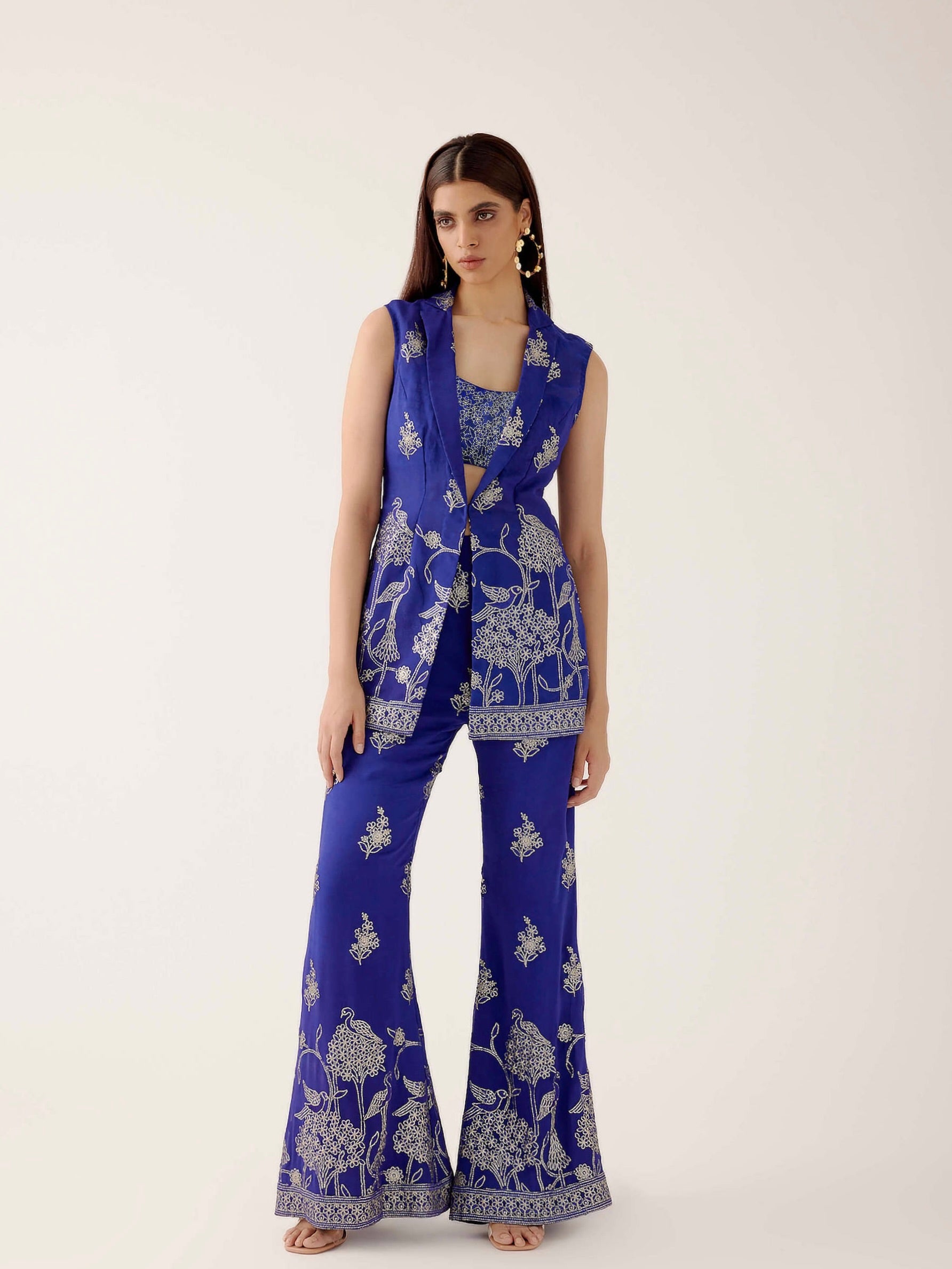 The embroidered Manali Set consists of a blue vest, bra top, and flared pants.