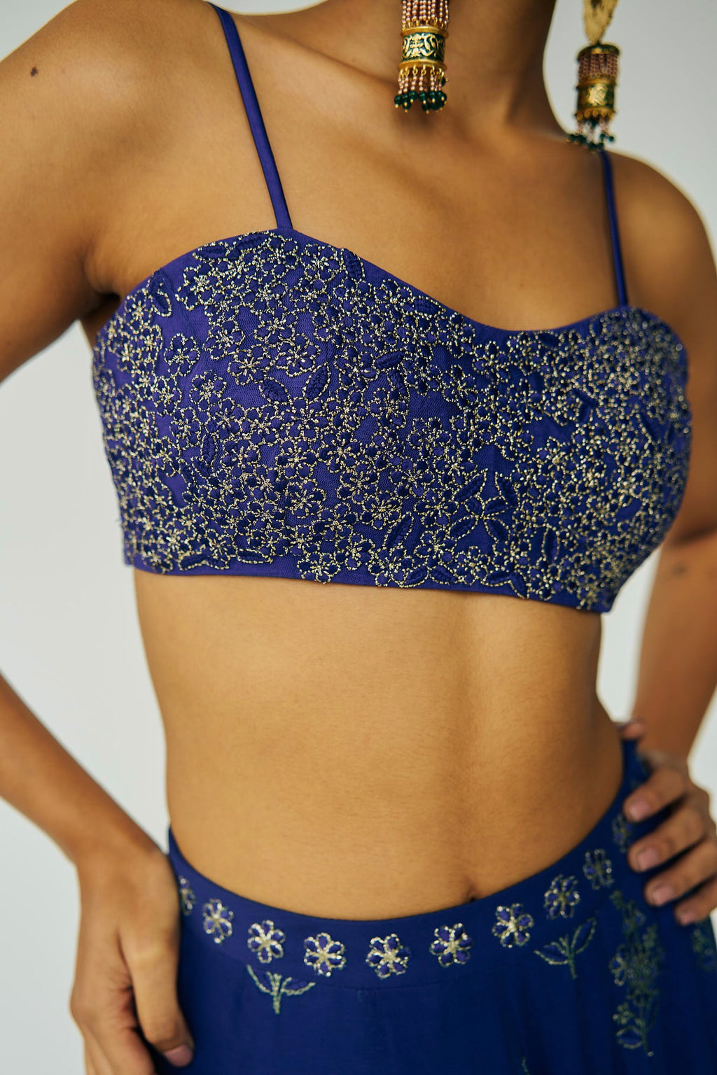 A woman wearing a bright blue embroidered top and skirt with an embroidered dupatta.