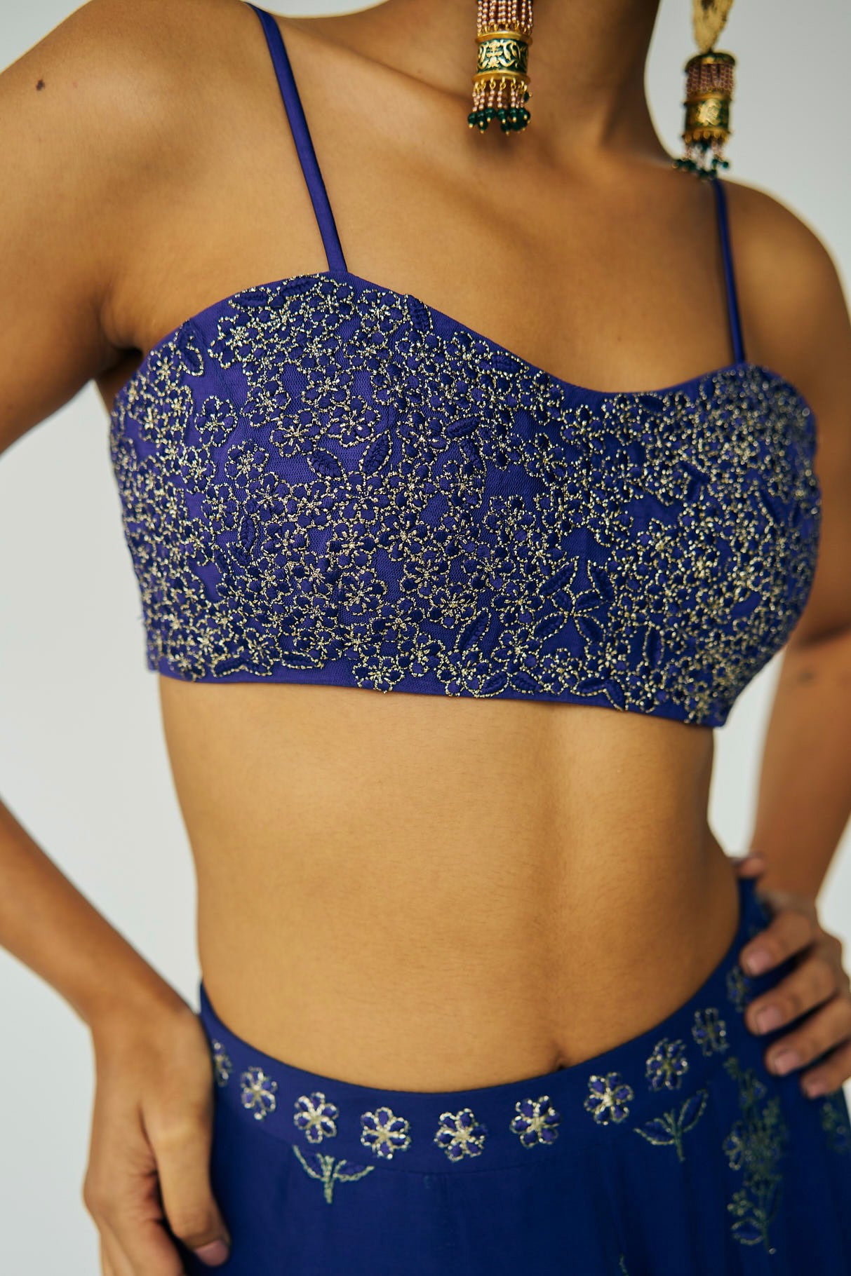 A woman wearing a bright blue embroidered top and skirt with an embroidered dupatta.