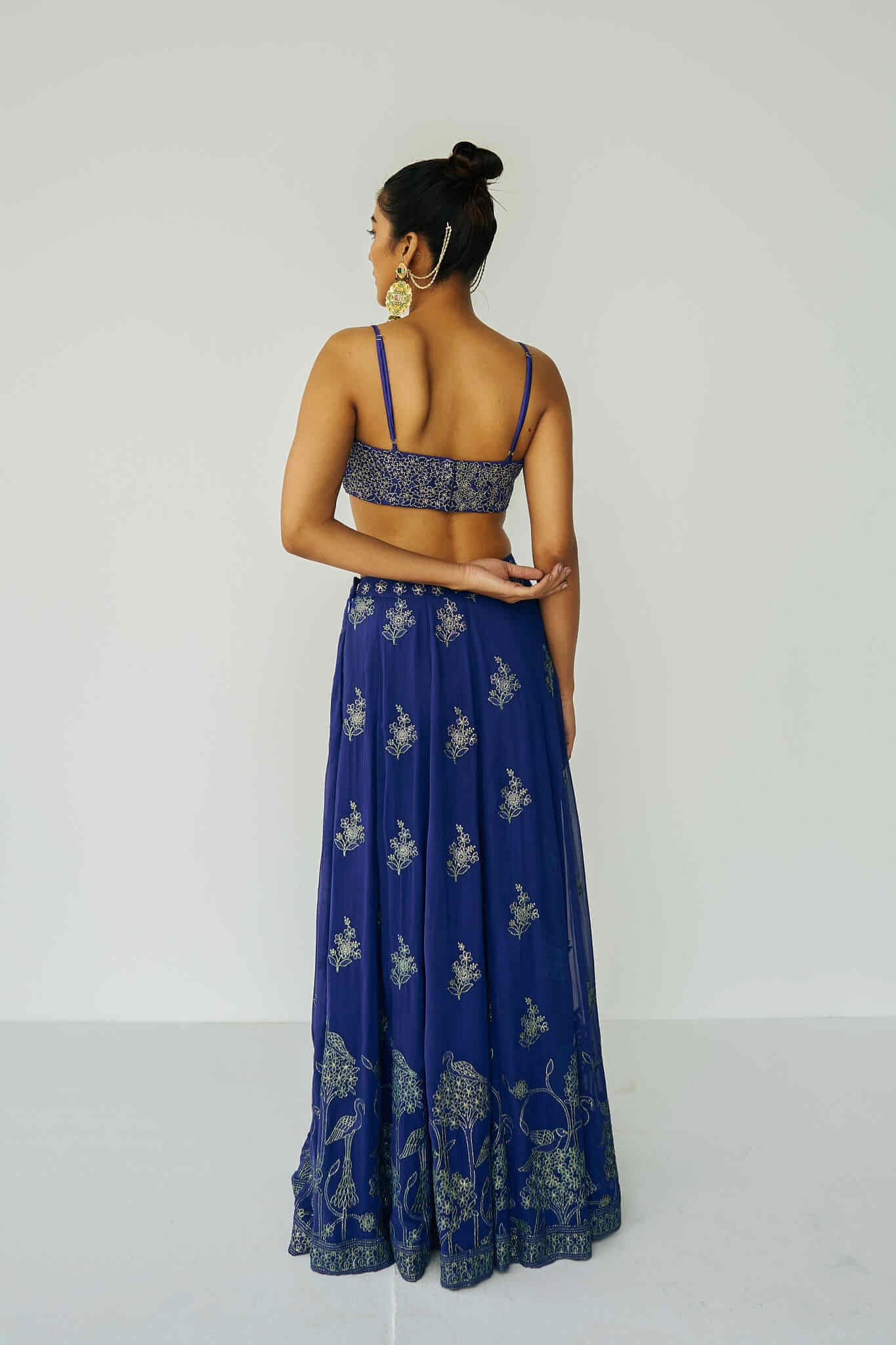 A woman wearing a bright blue embroidered top and skirt with an embroidered dupatta.