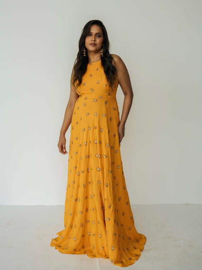 The Nila Anarkali has a halter neck-cut bodice, flowing waistline, and is paired with a contrasting silk crepe dupatta.