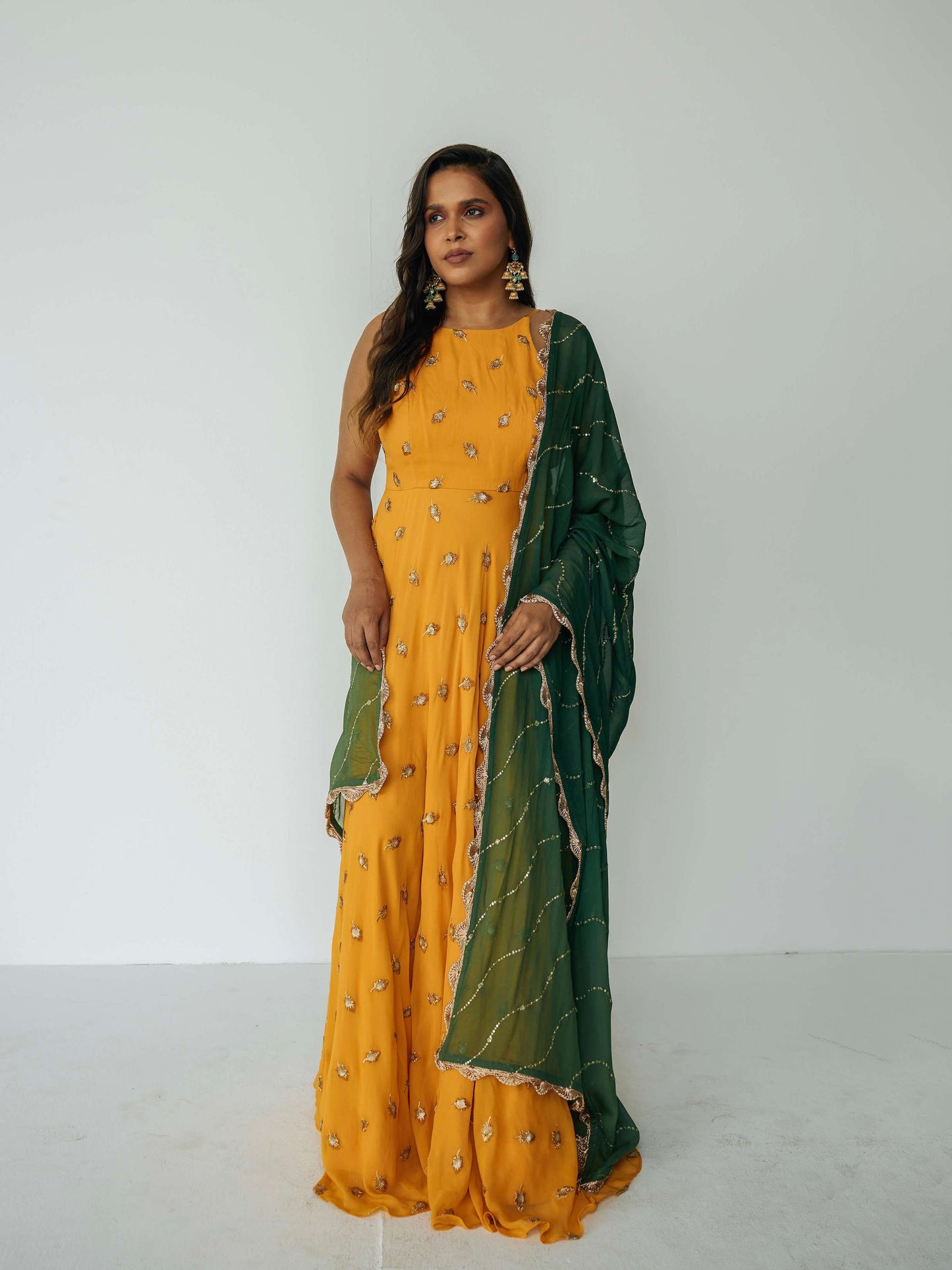 The Nila Anarkali has a halter neck-cut bodice, flowing waistline, and is paired with a contrasting silk crepe dupatta.