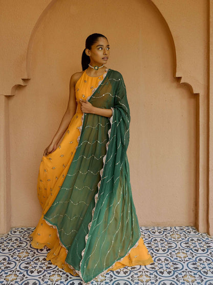 The Nila Anarkali has a halter neck-cut bodice, flowing waistline, and is paired with a contrasting silk crepe dupatta.