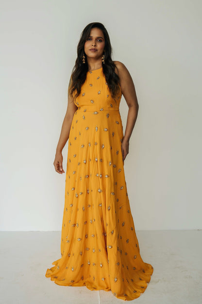 The Nila Anarkali has a halter neck-cut bodice, flowing waistline, and is paired with a contrasting silk crepe dupatta.