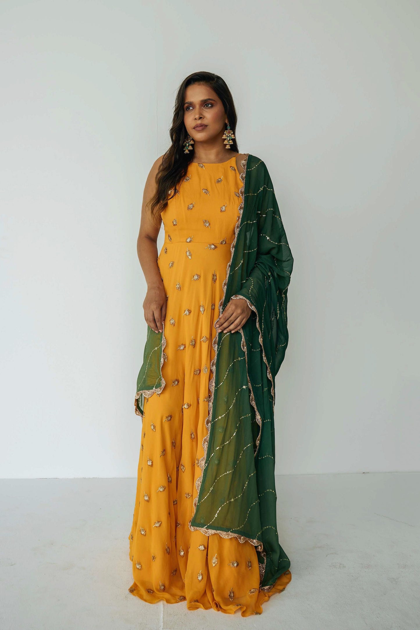 The Nila Anarkali has a halter neck-cut bodice, flowing waistline, and is paired with a contrasting silk crepe dupatta.