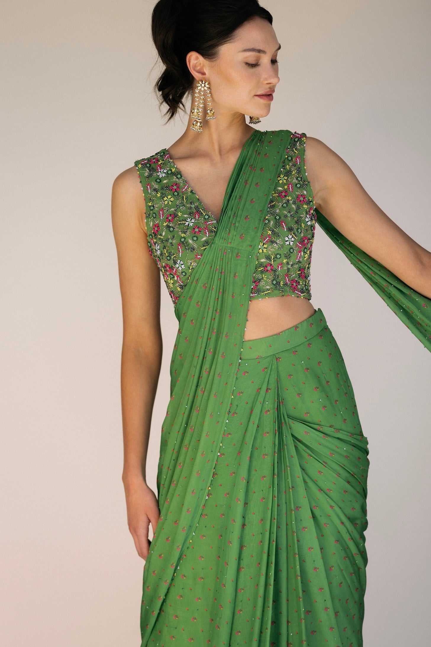 This saree has a hand-embroidered cropped top with intricate beadwork and sequins and is paired with a skirt featuring attached wraparound draping. This outfit is prestitched, so you can put it together in 30 seconds or less.